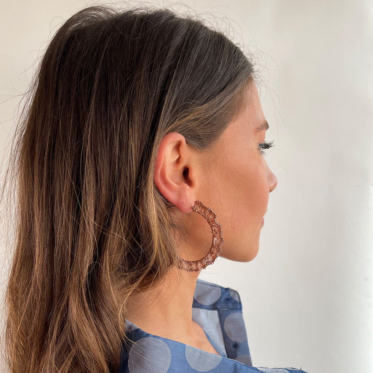 Jacqueline large lace hoop earrings in rose gold on a model.