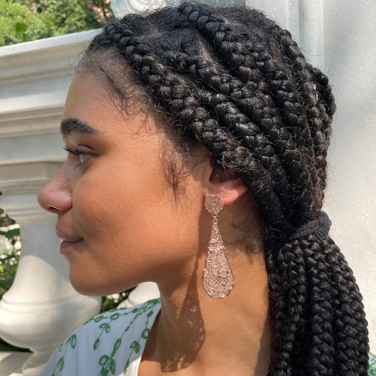 Teardrop lace earrings dipped in rose gold on model.