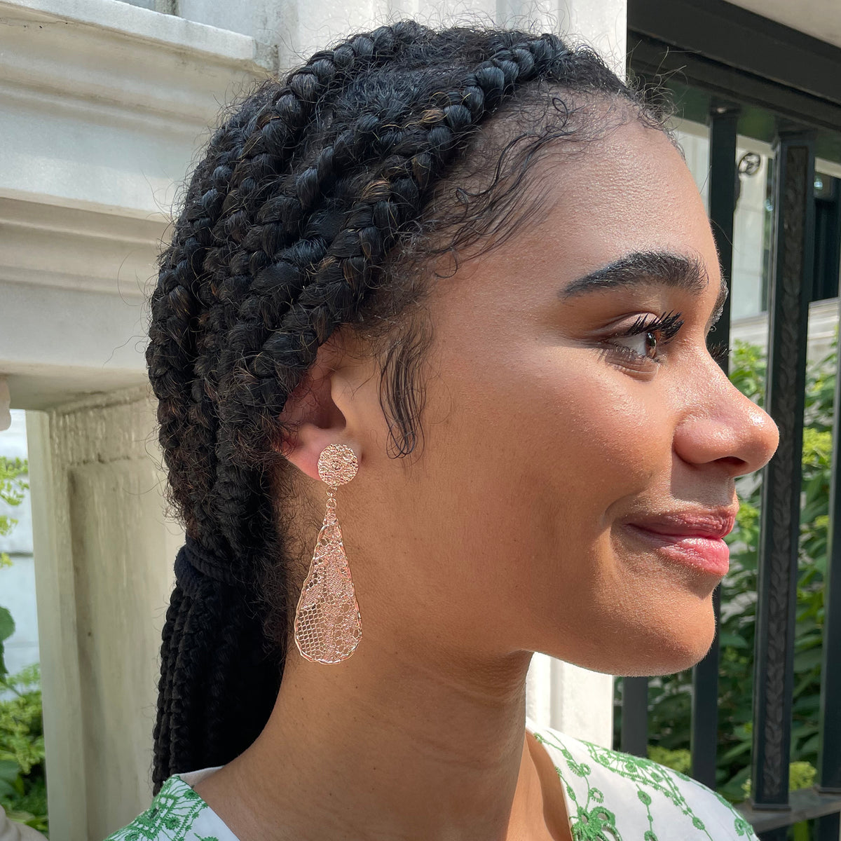 Teardrop lace earrings dipped in rose gold on model.