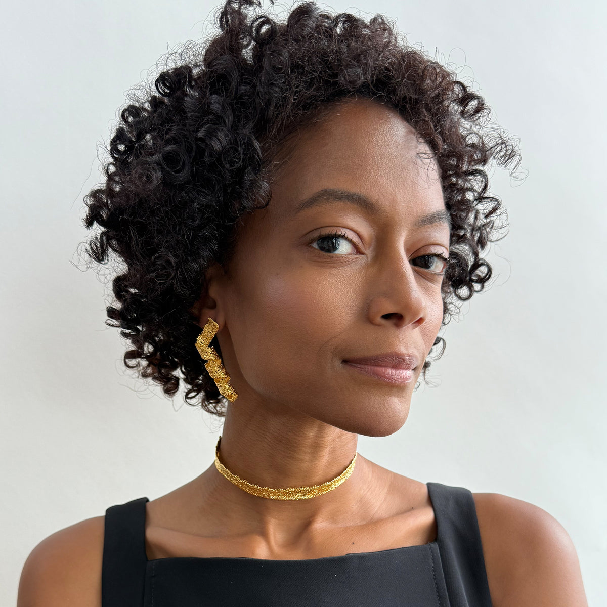 Model wearing Azeline lace swirl and drop earrings in 24k gold.