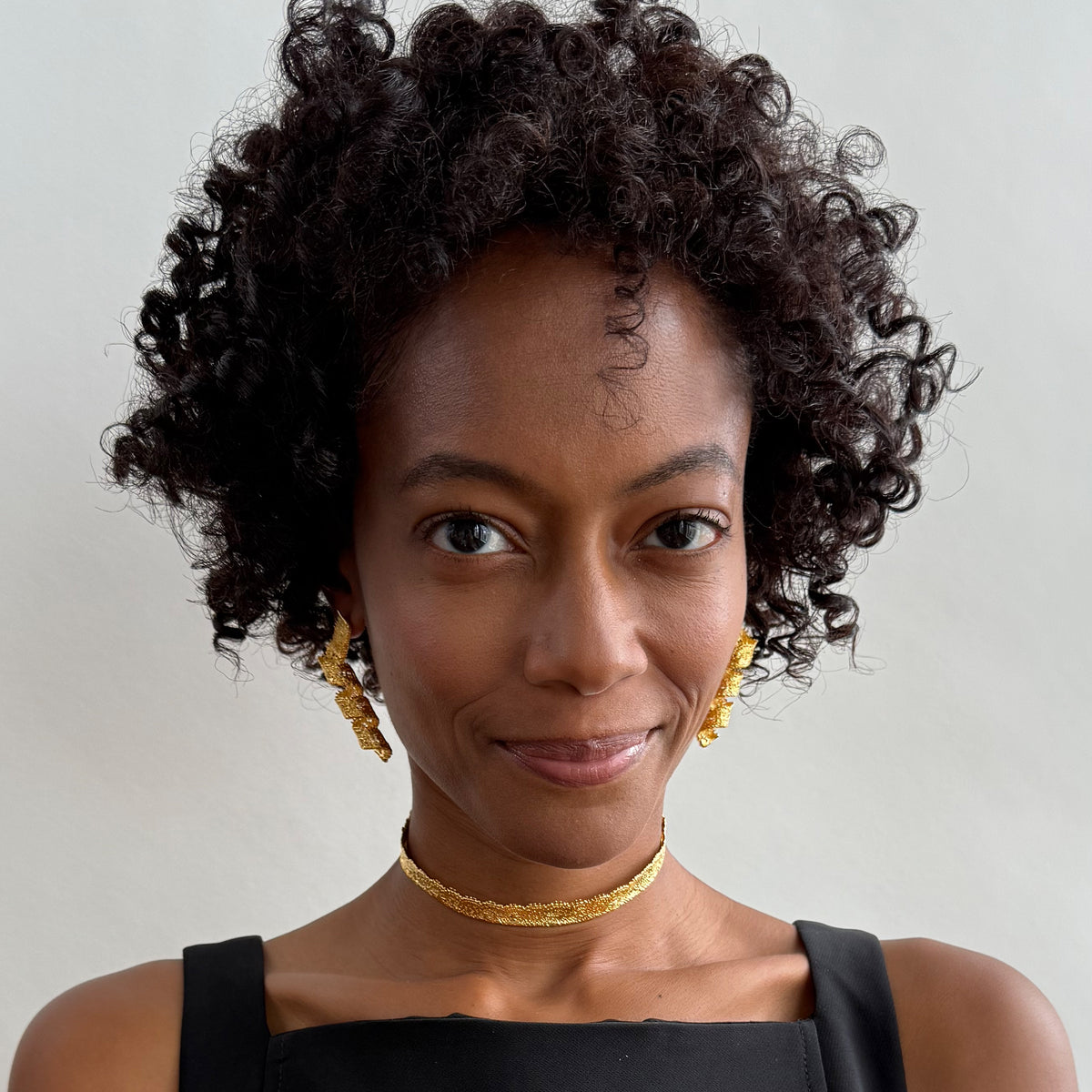 Model wearing Azeline lace swirl and drop earrings in 24k gold.