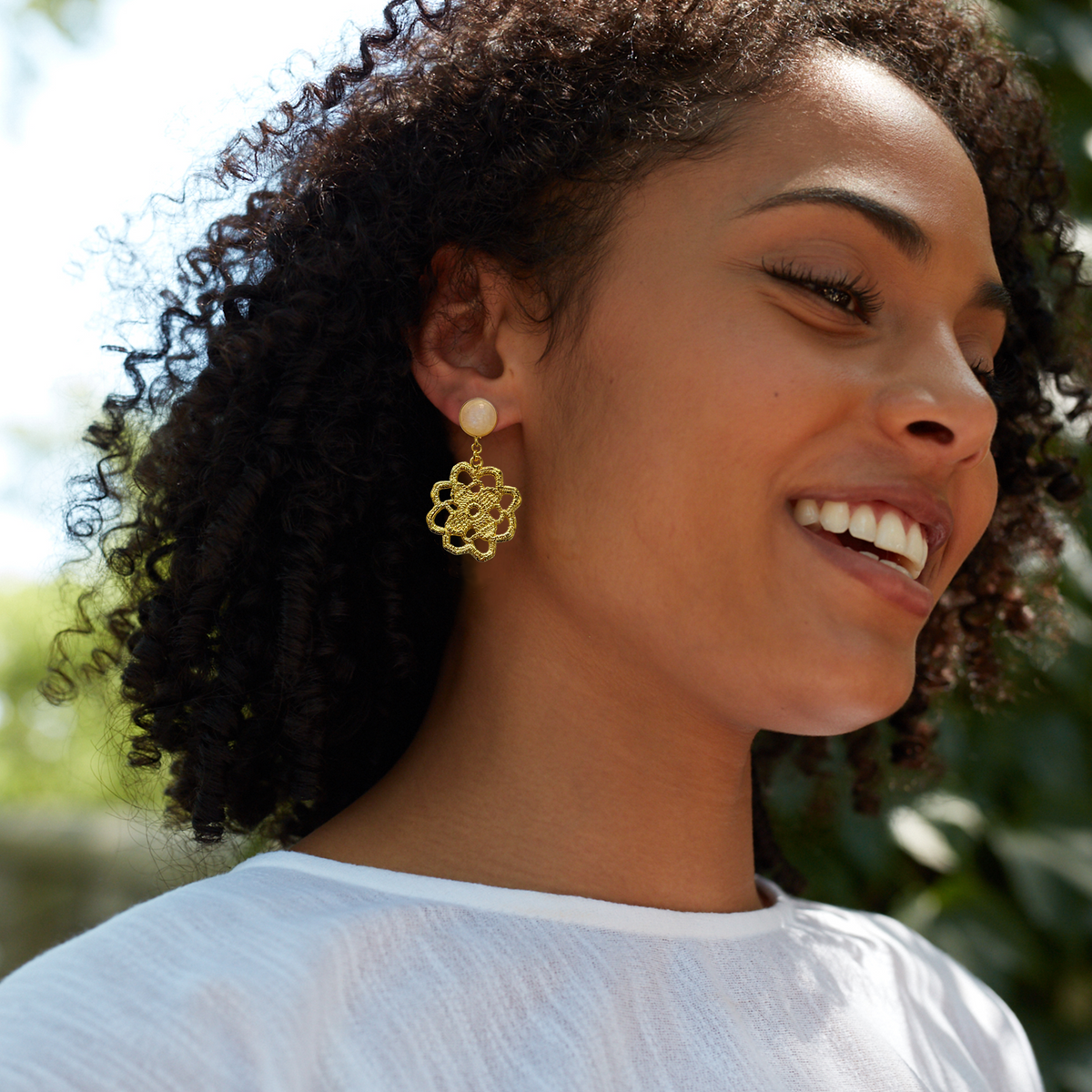 Lace flower earrings made from repurposed lace dipped in 24k gold with 10mm moonstone cabochons worn by a model.