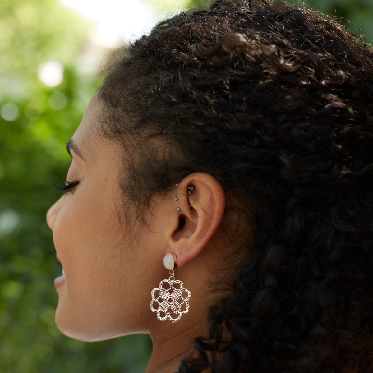Lace flower earrings made from repurposed lace dipped in rose gold with 10mm moonstone cabochons worn by a model.