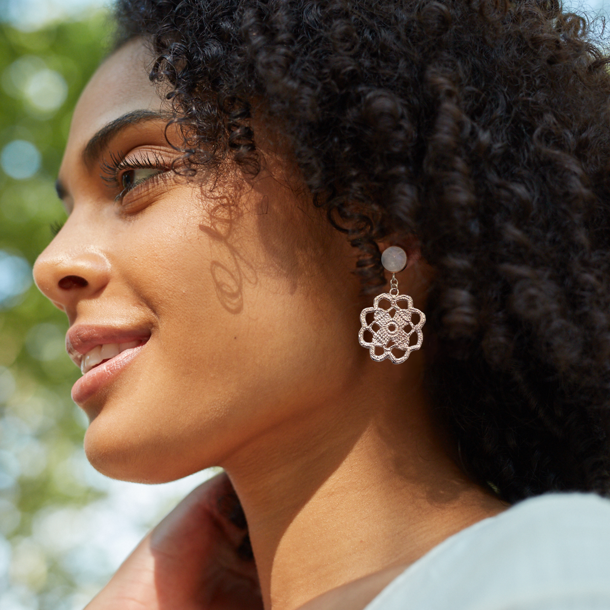 Lace flower earrings made from repurposed lace dipped in rose gold with 10mm moonstone cabochons worn by a model.