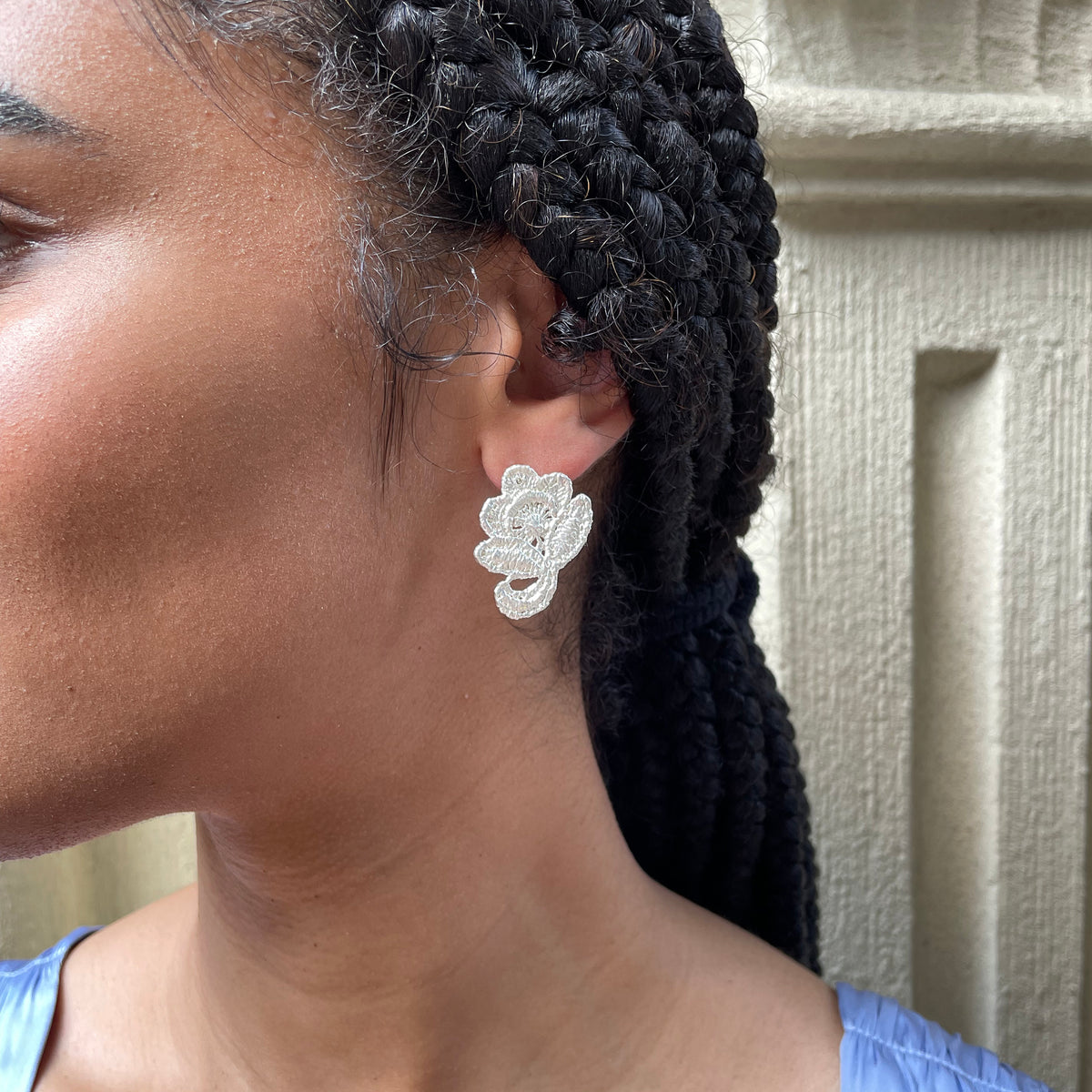 Flower stud earrings made from American lace dipped in sterling silver on a model.