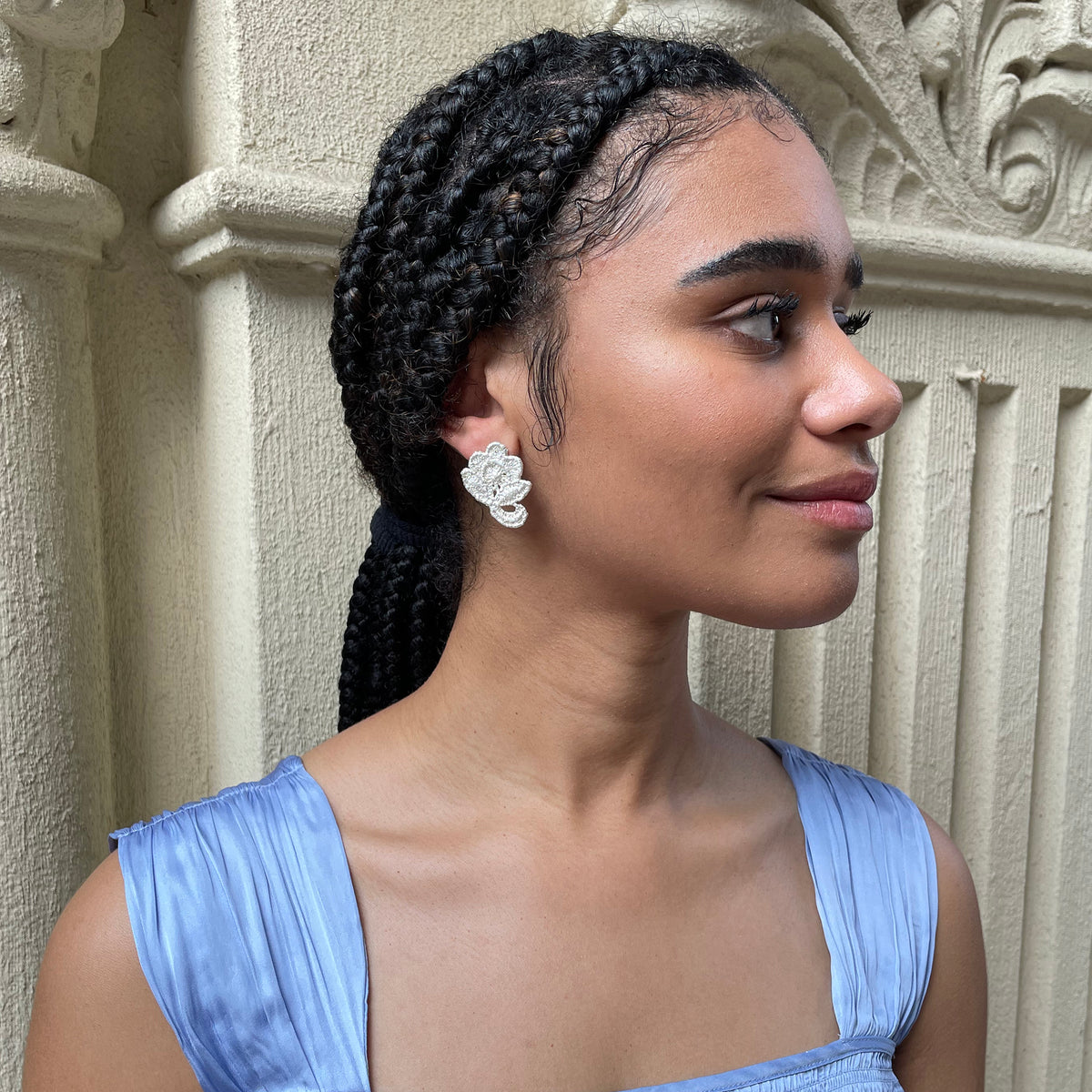 Flower stud earrings made from American lace dipped in sterling silver on a model.