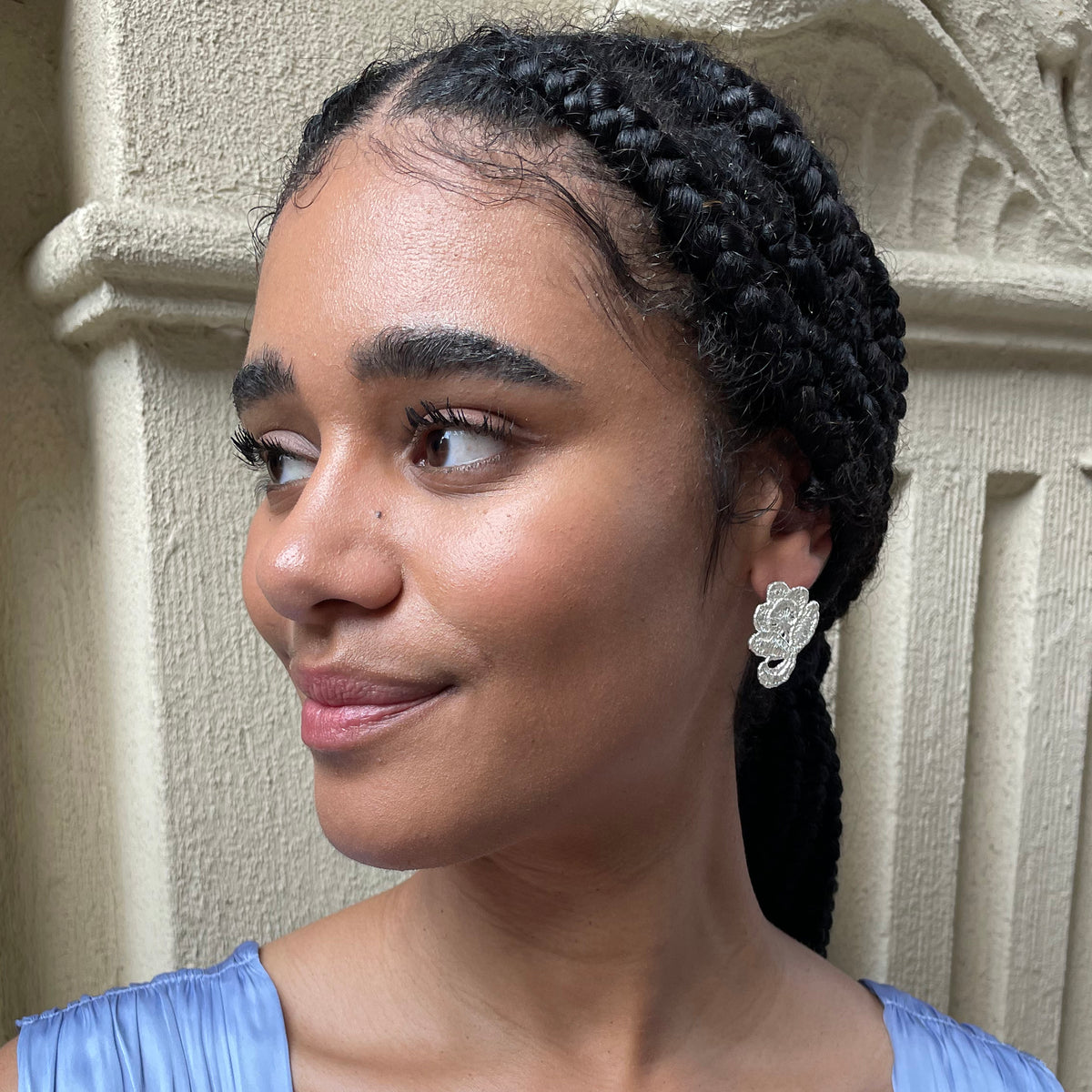 Flower stud earrings made from American lace dipped in sterling silver on a model.