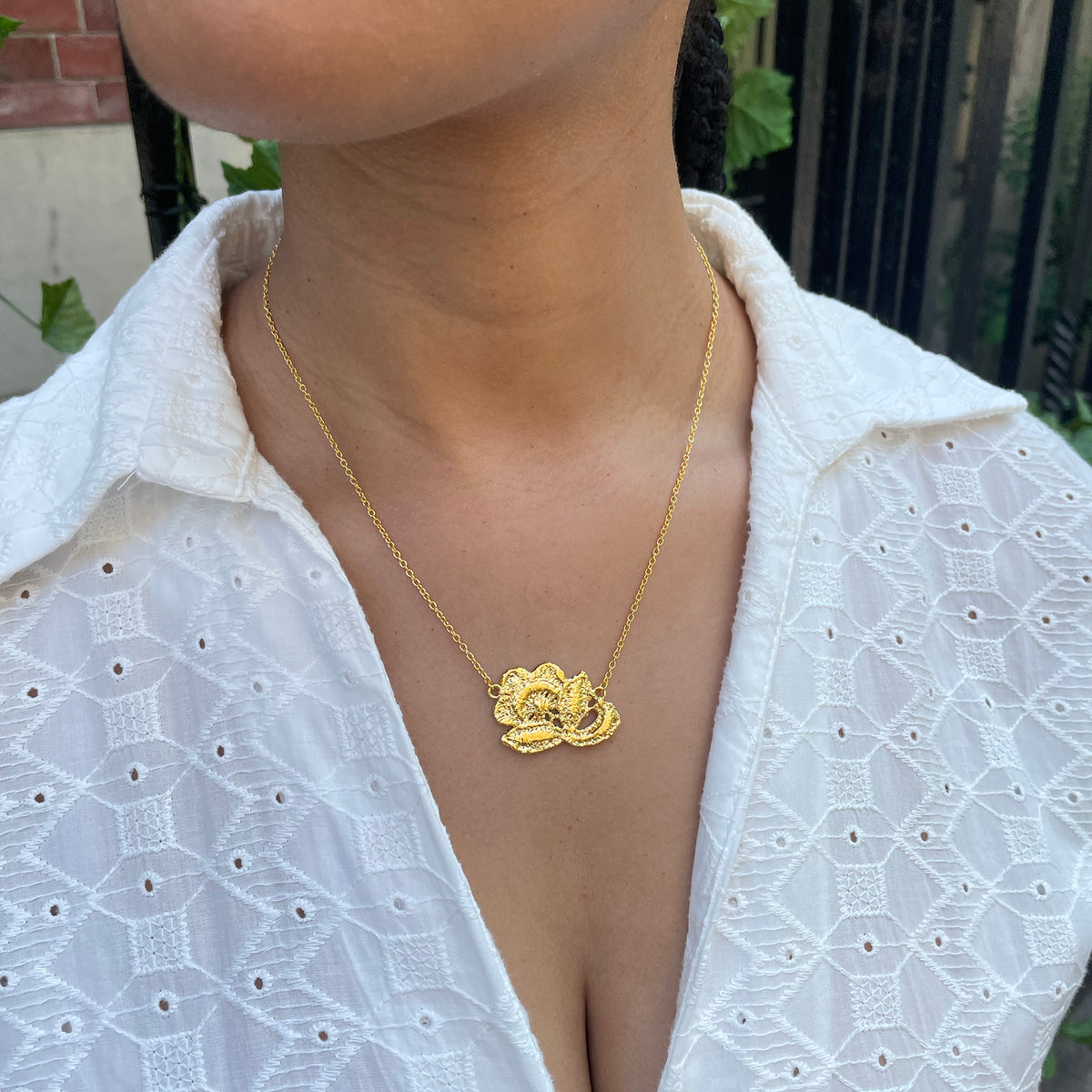 Fine lace rose necklace in 24k gold on model.