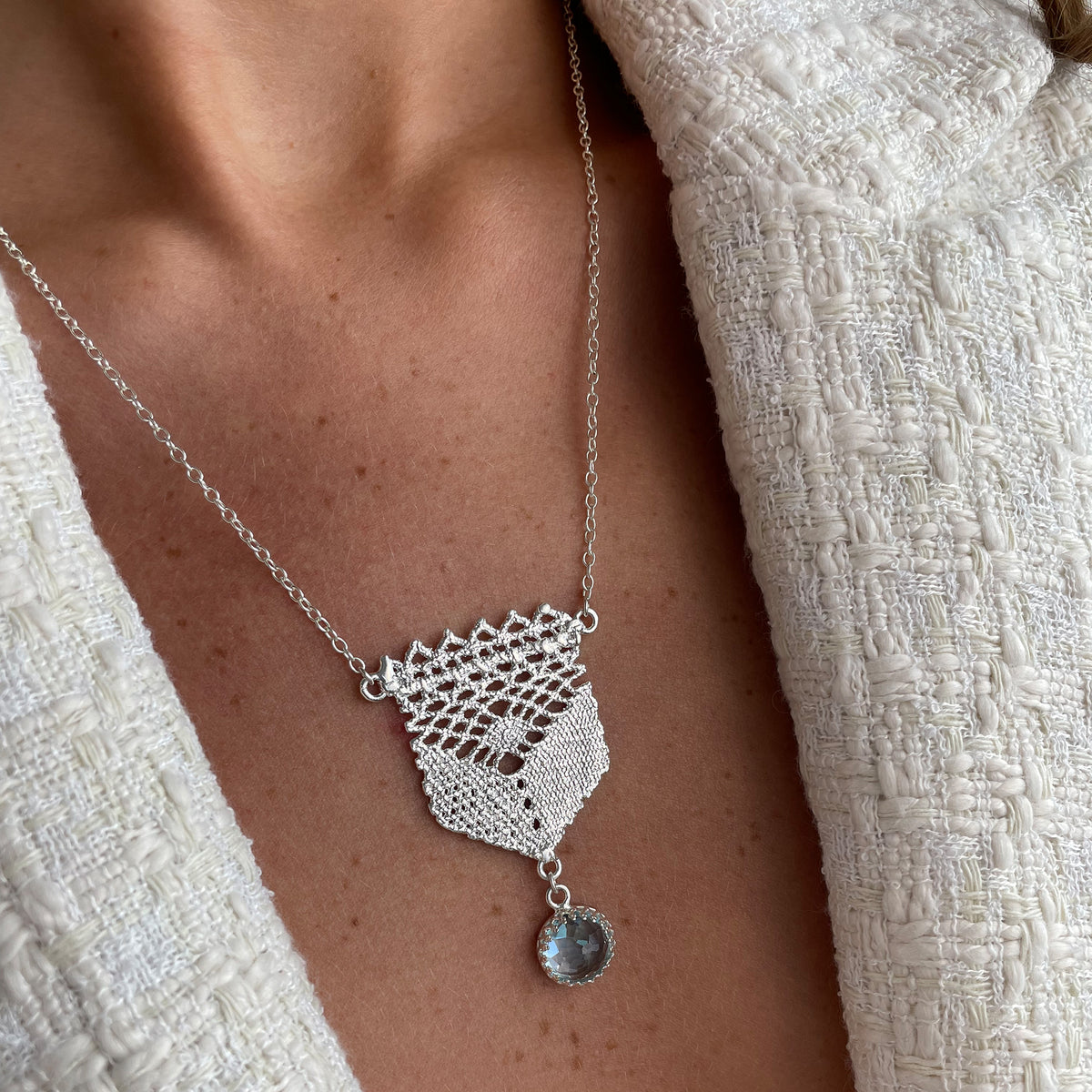 Lace pendant in silver with a faceted Aquamarine stone on a model.
