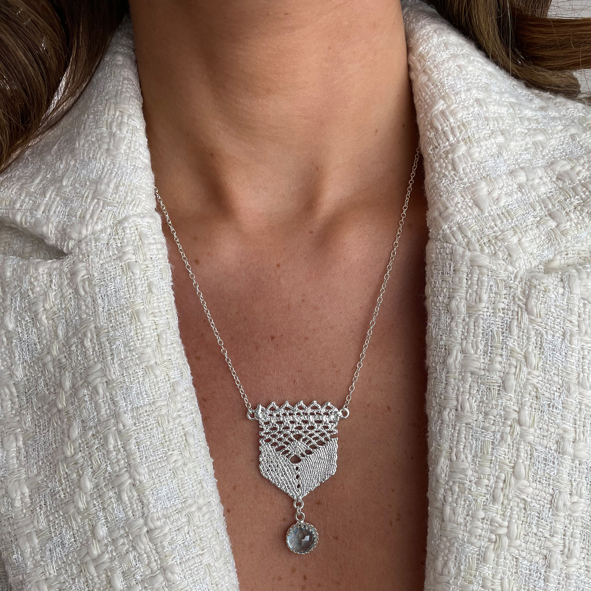 Lace pendant in silver with a faceted Aquamarine stone on a model.