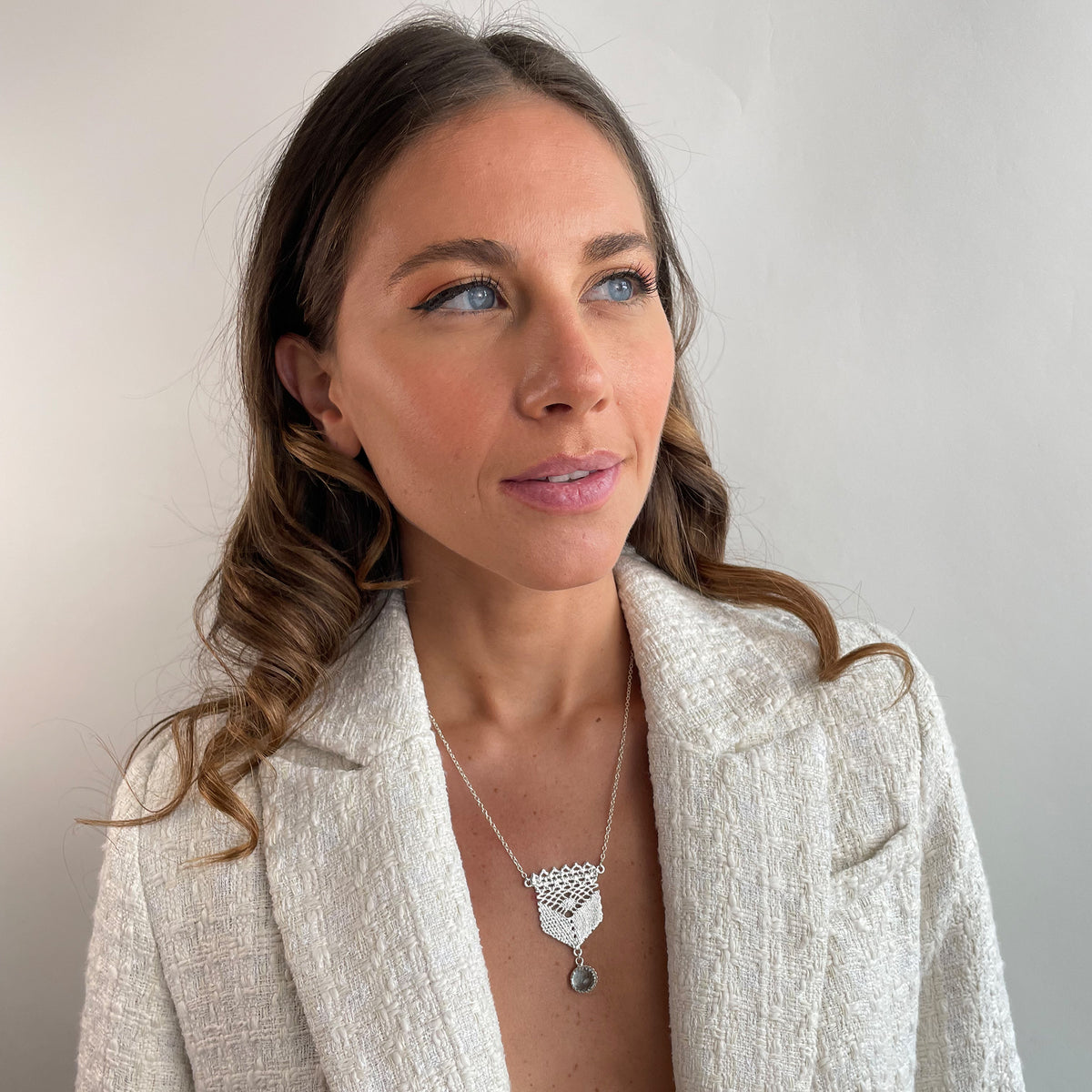 Lace pendant in silver with a faceted Aquamarine stone on a model.