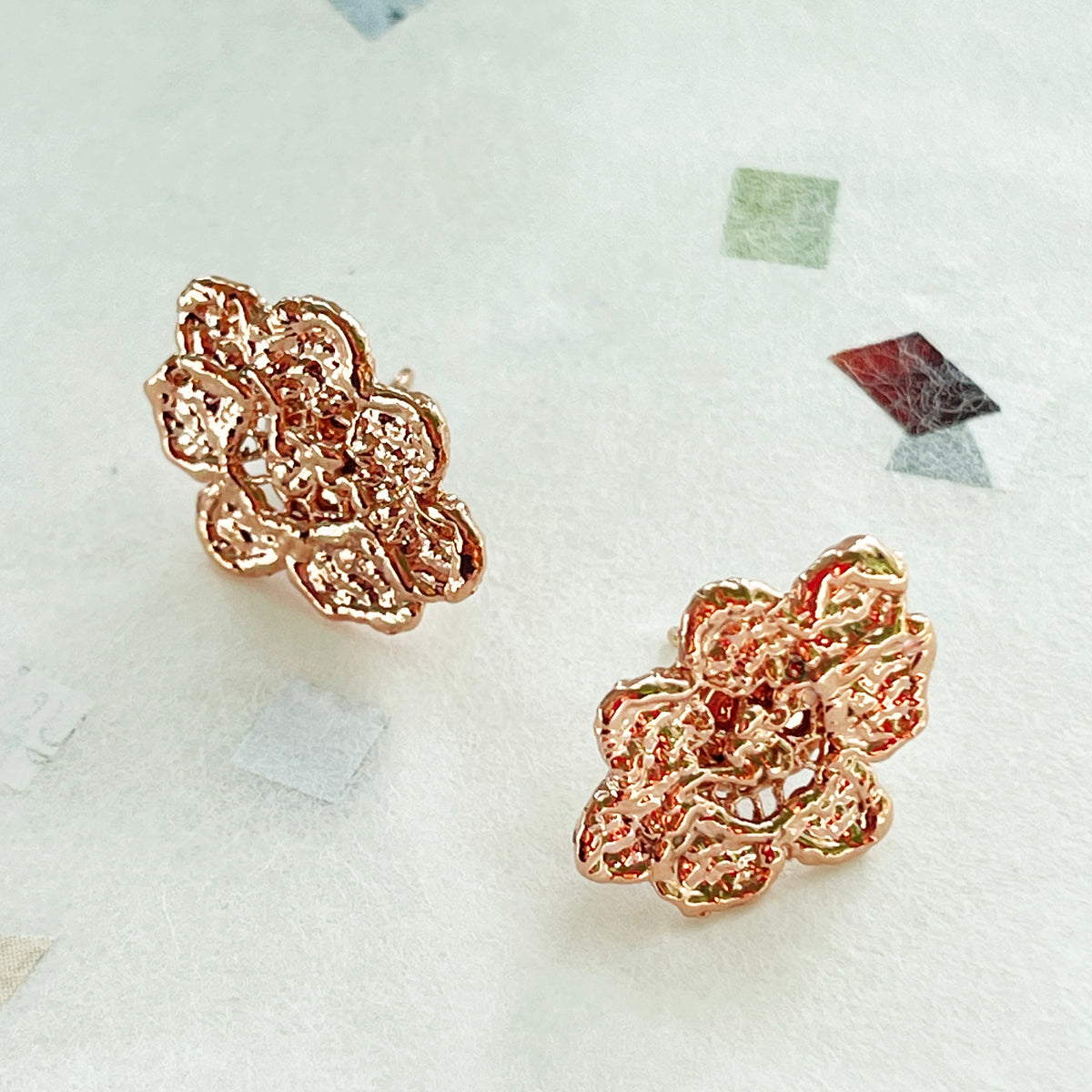 Small, exquisite stud earring in the shape of a lace flower dipped in rose gold.