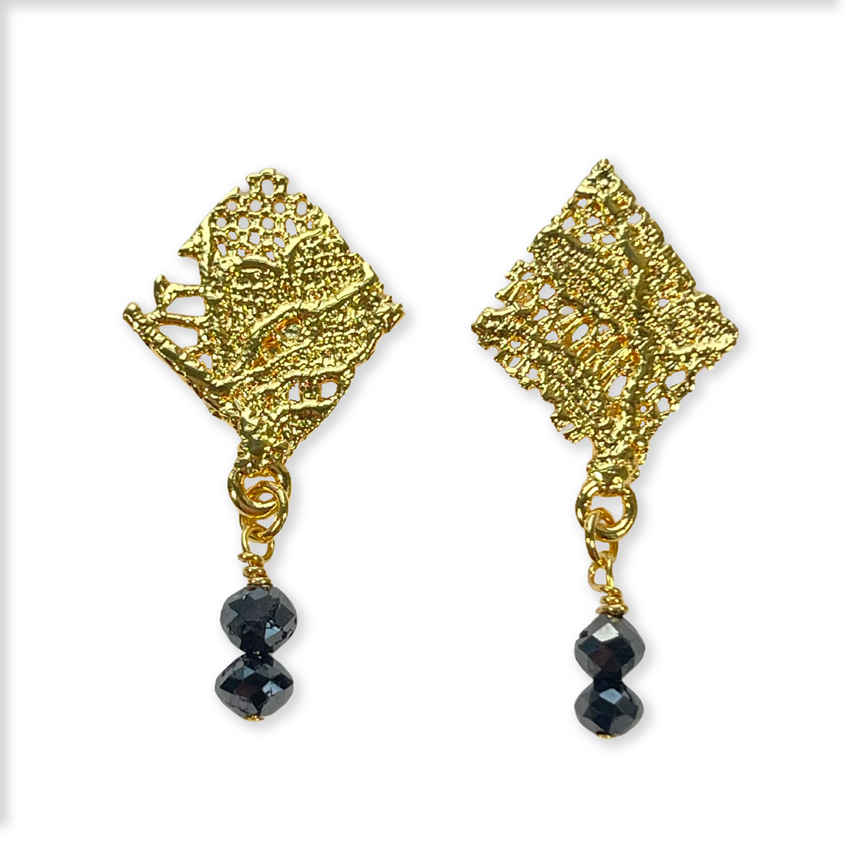 Diamond shaped lace earrings in 24k gold with two faceted black diamonds.