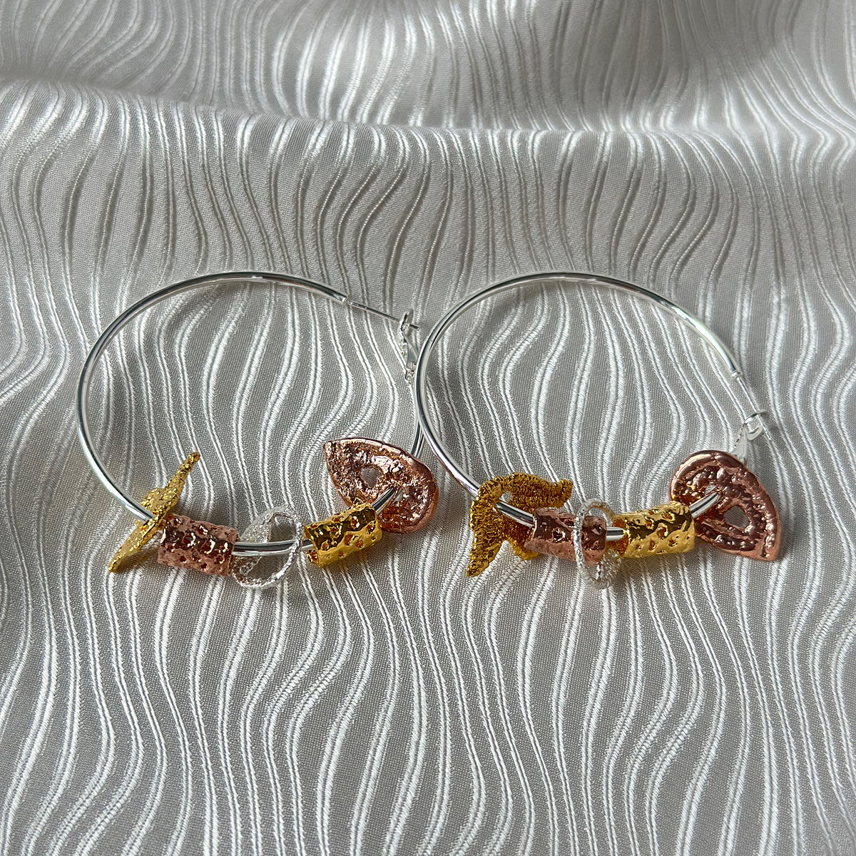 Pair of silver hoop earrings with lace charms dipped in 24k gold, rose gold and sterling silver.