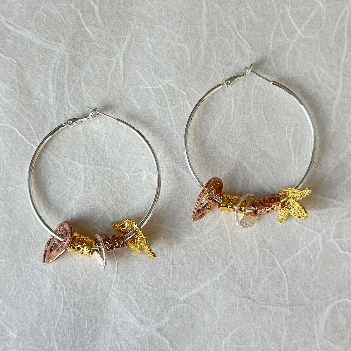 Pair of silver hoop earrings with lace charms dipped in 24k gold, rose gold and sterling silver.