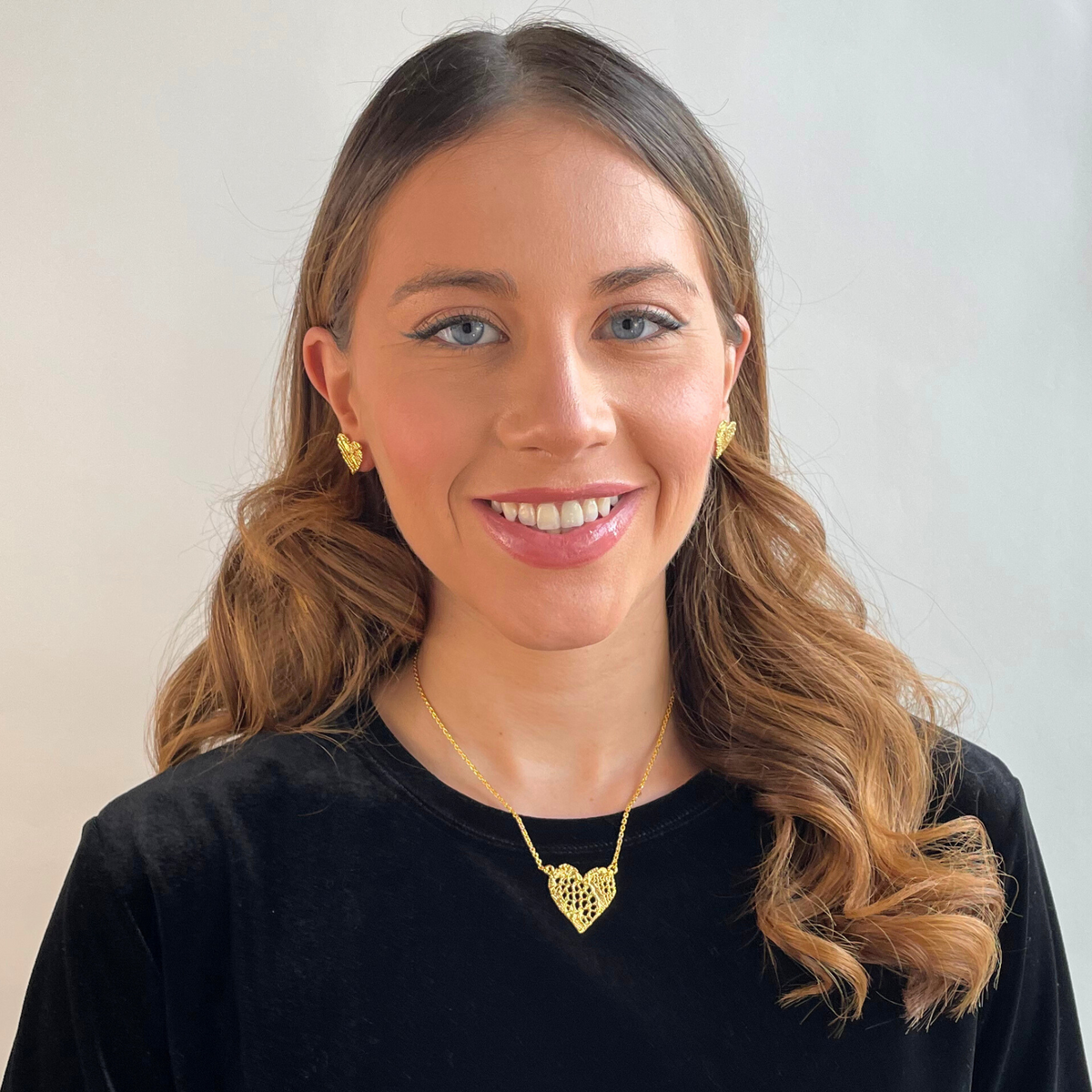 Remy lace heart necklace and Addie lace earrings in 24k gold worn by a model.