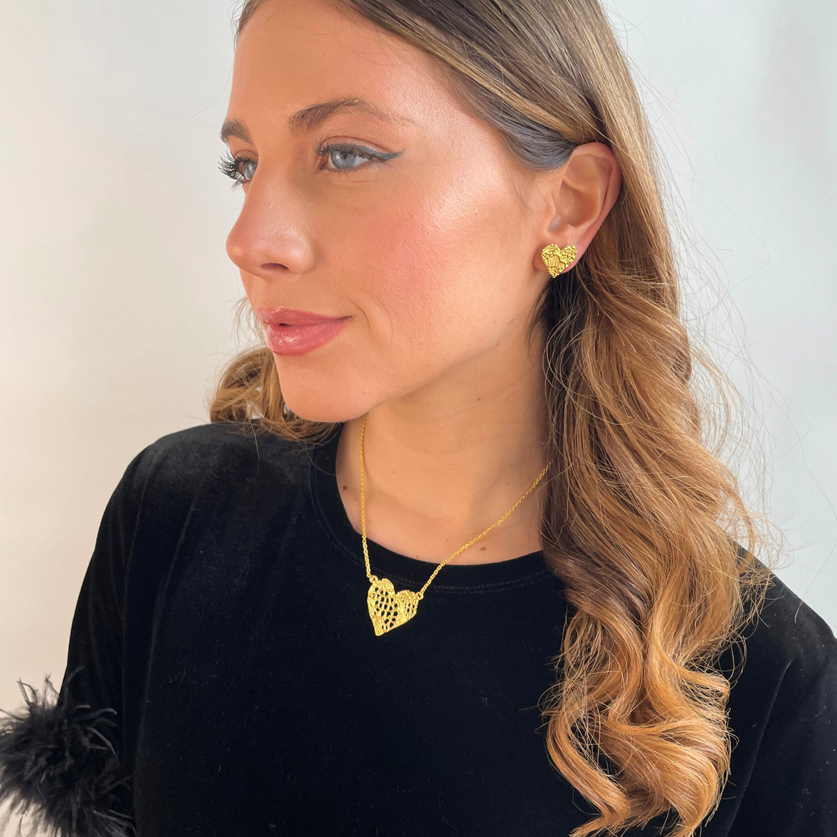 Remy lace heart necklace and Addie lace earrings in 24k gold worn by a model.