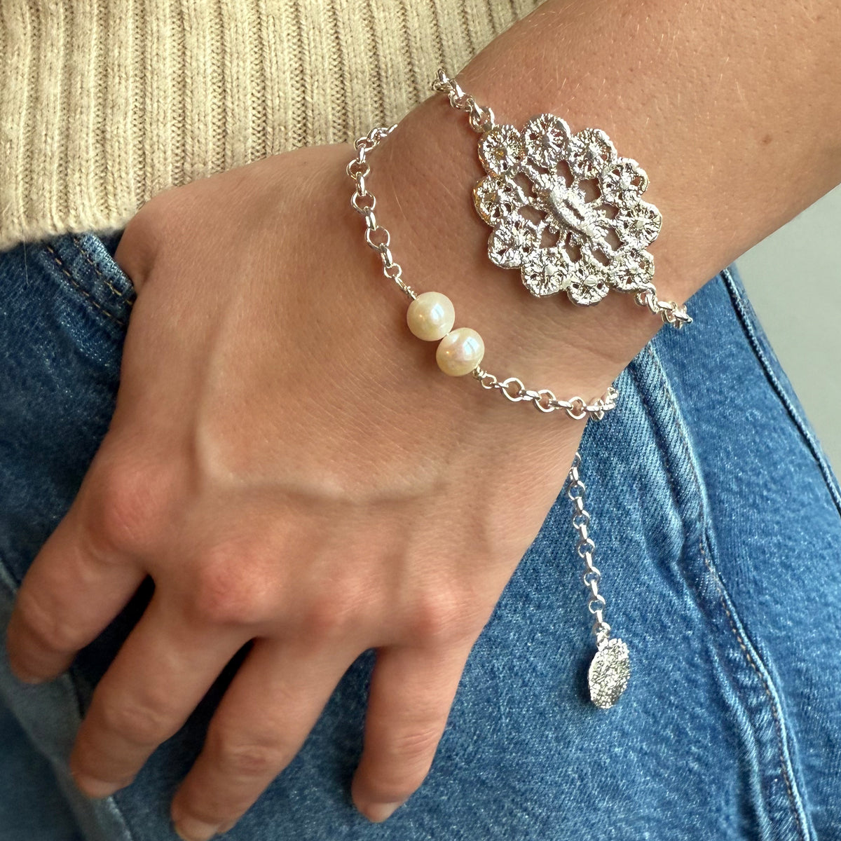 Model wearing and exquisite chain bracelet with lace medaillon in sterling silver and two white pearls.