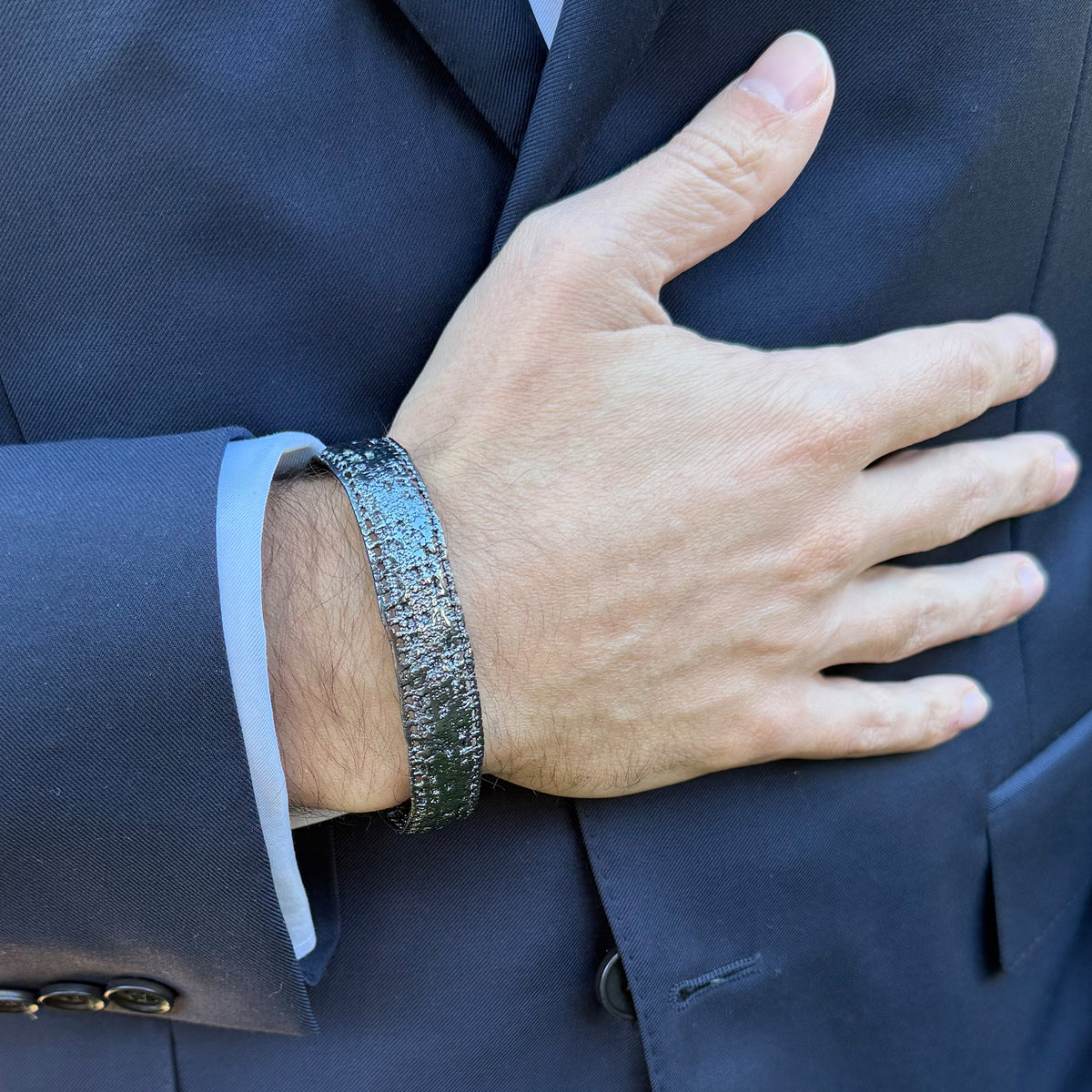 A model wearing a men's lace bracelet in dipped oxidized sterling silver.