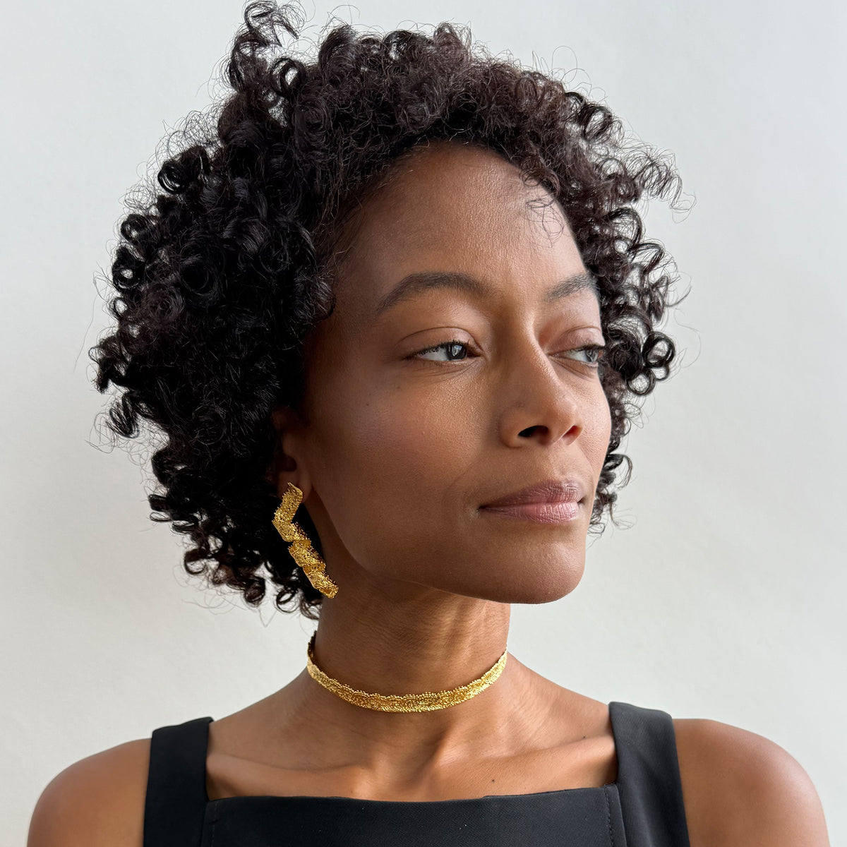 Model wearing Azeline lace swirl and drop earrings in 24k gold.