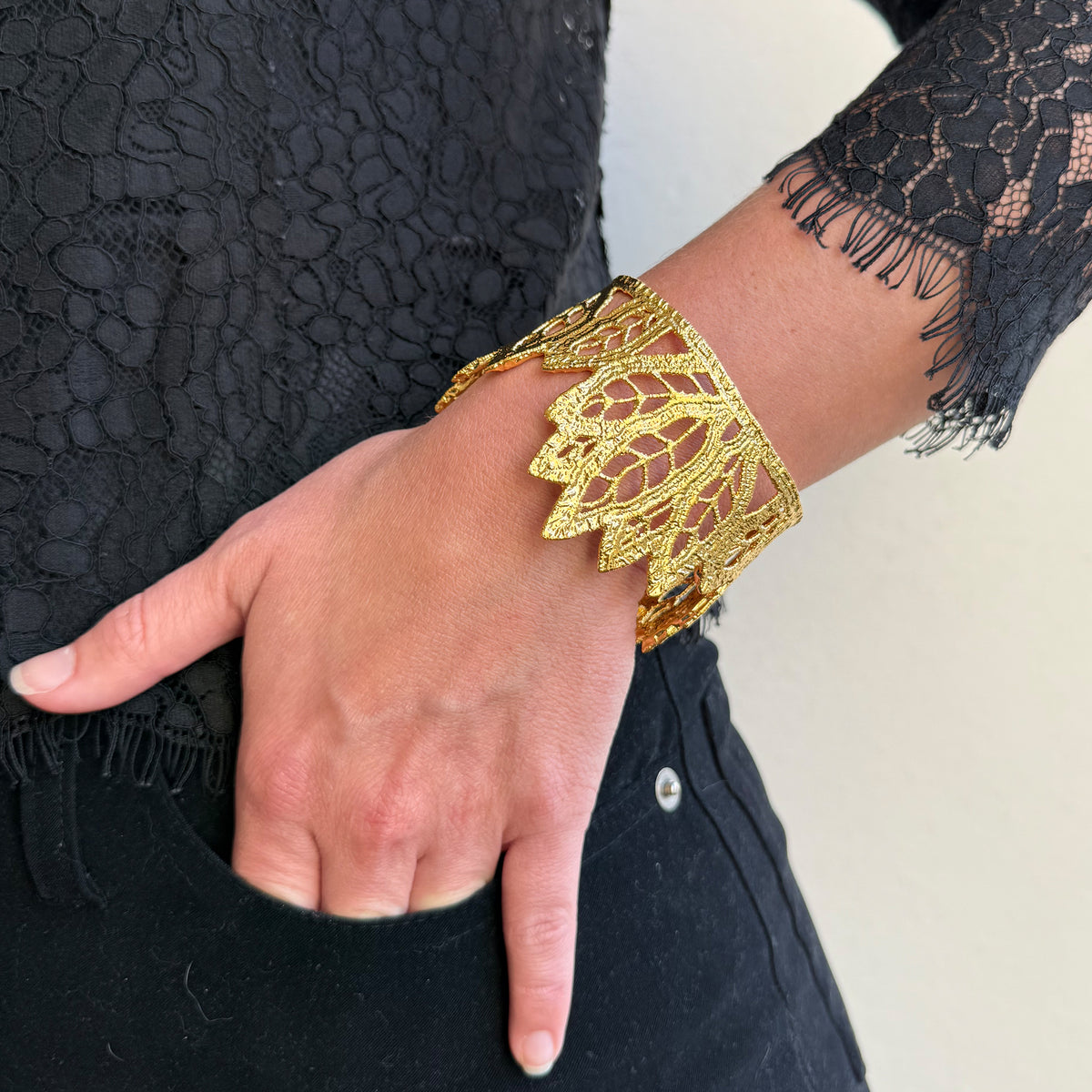 A model wearing a lace leaf bracelet in dipped 24k gold.