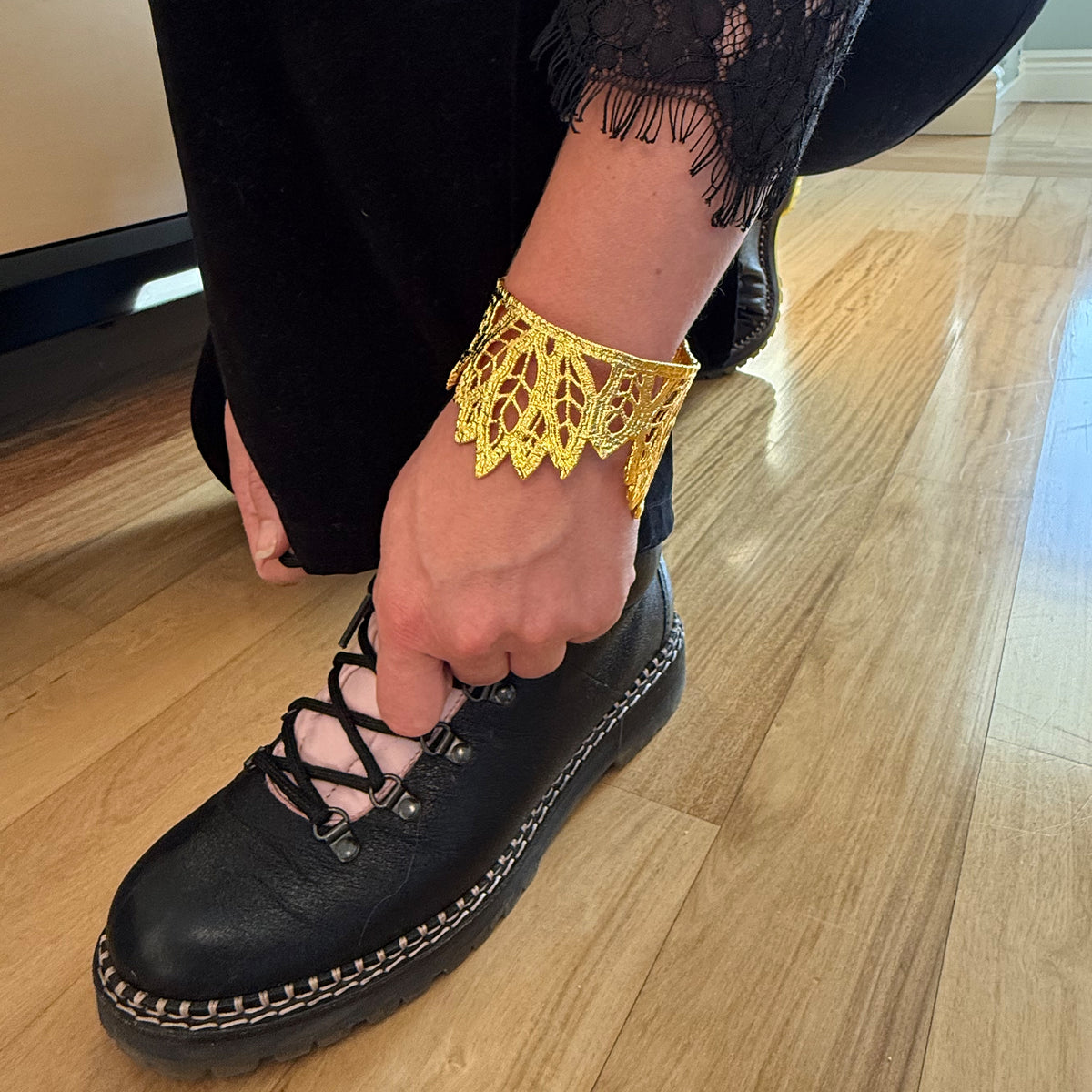 A model wearing a lace leaf bracelet in dipped 24k gold.