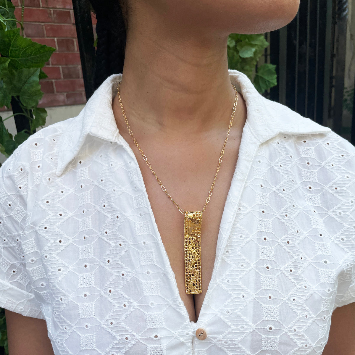 Lace pendant necklace solidified in 24k gold on model.