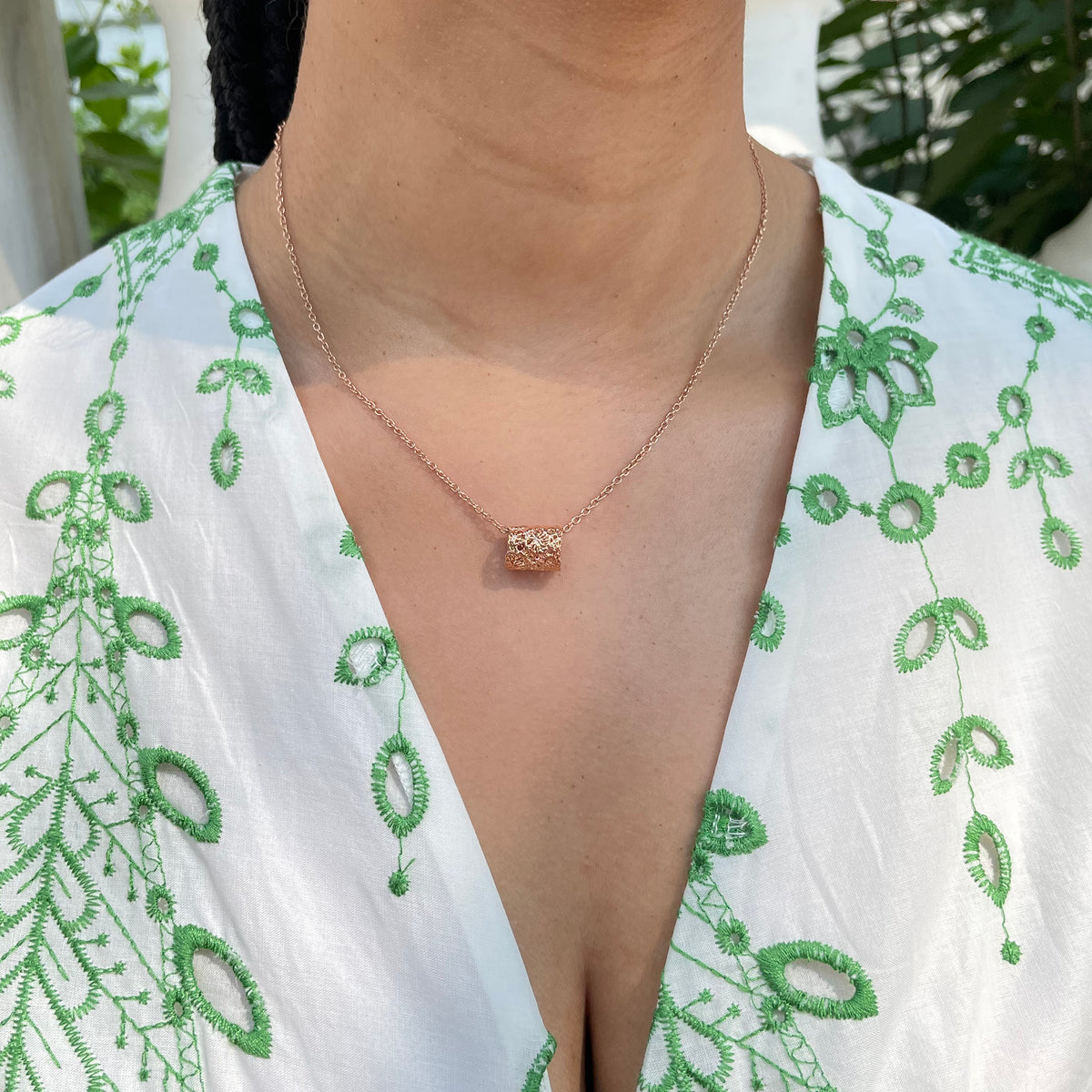 Small lace charm necklace in rose gold on model.