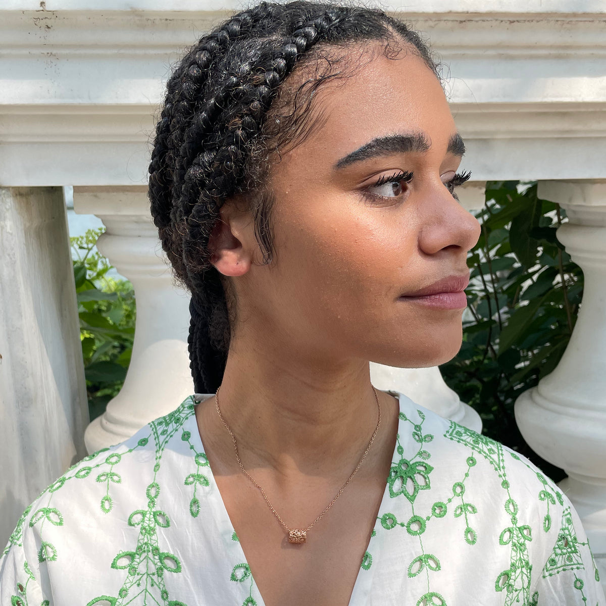 Small lace charm necklace in rose gold on model.