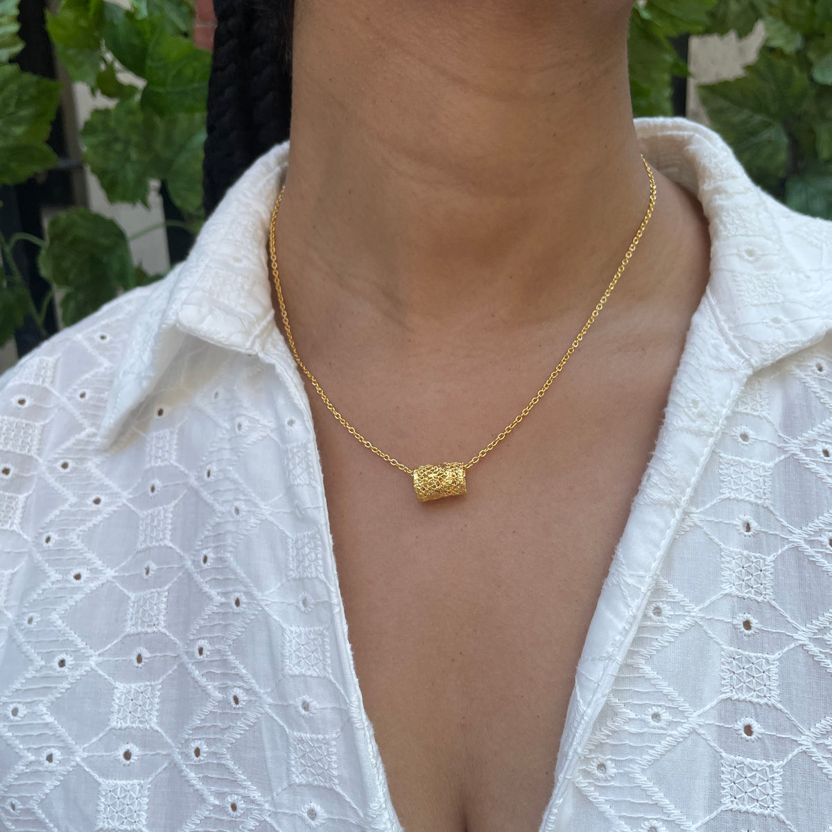 Small lace charm necklace in 24k gold on model.