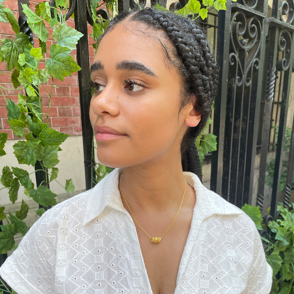 Small lace charm necklace in 24k gold on model.