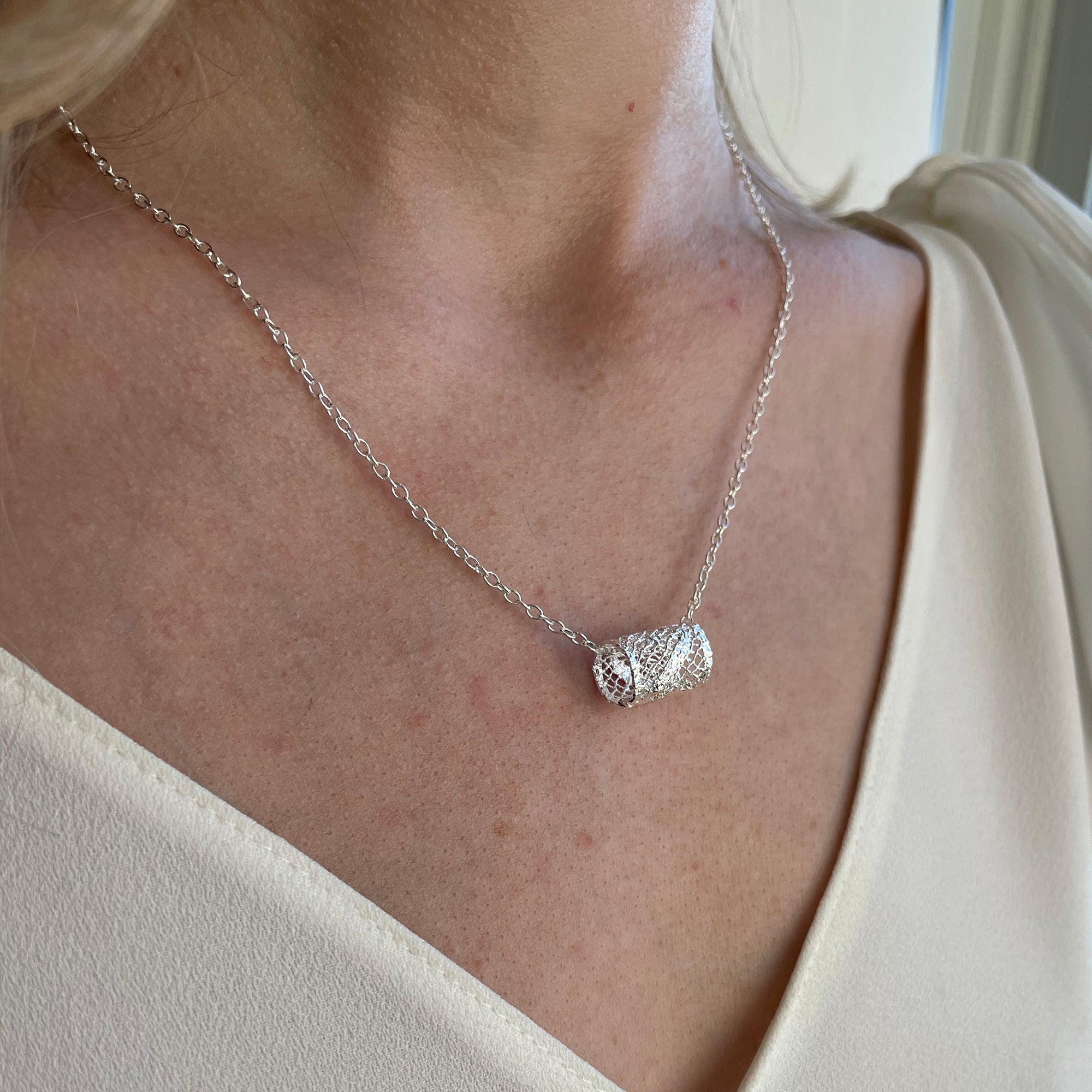 Small lace charm necklace with lace cylinder in 24k gold.