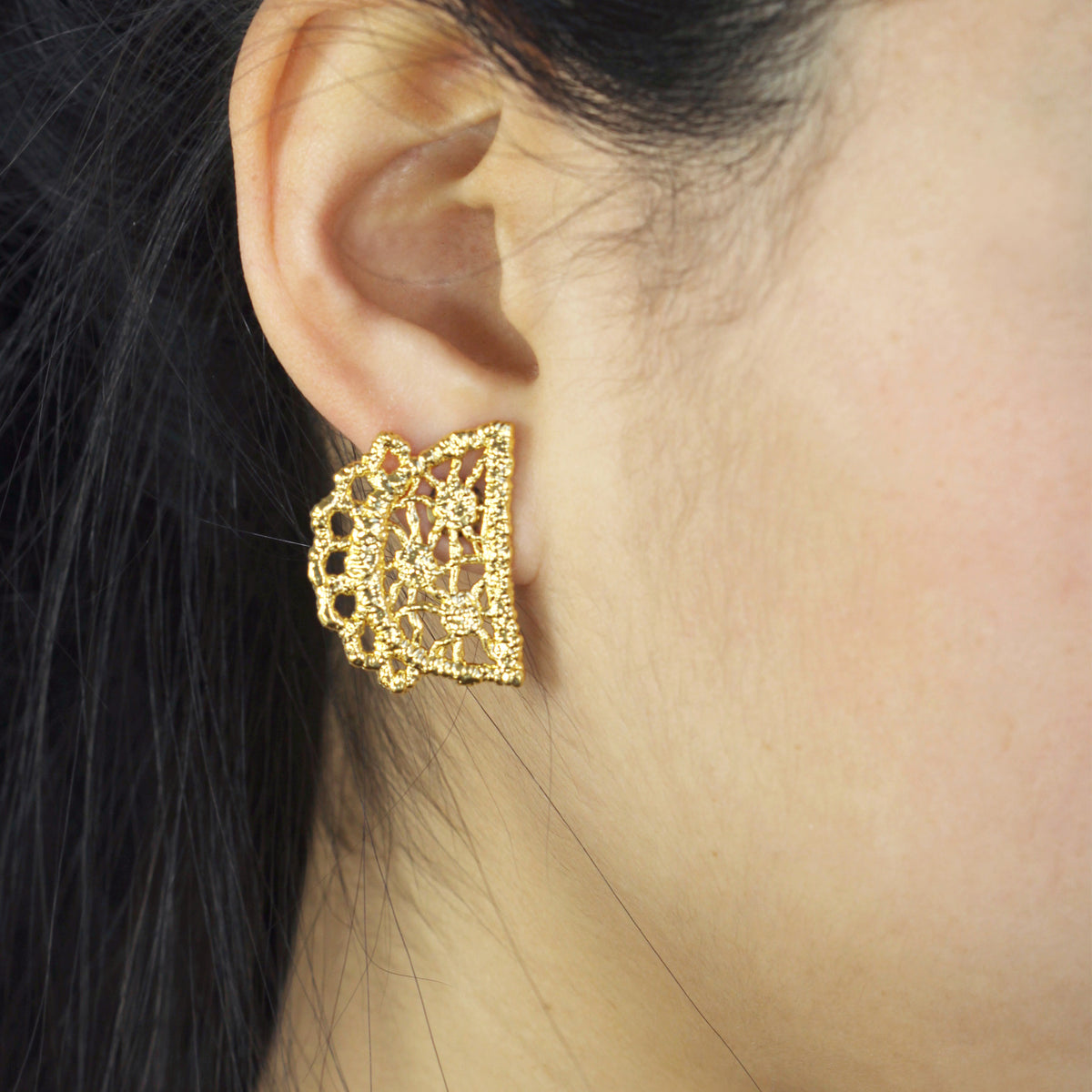 Half-moon lace stud earrings in 24k gold on a model.
