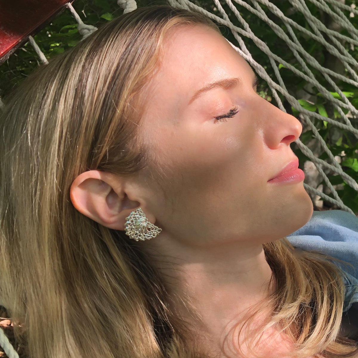 Model wearing half moon stud earrings made from Swedish lace dipped in sterling silver.
