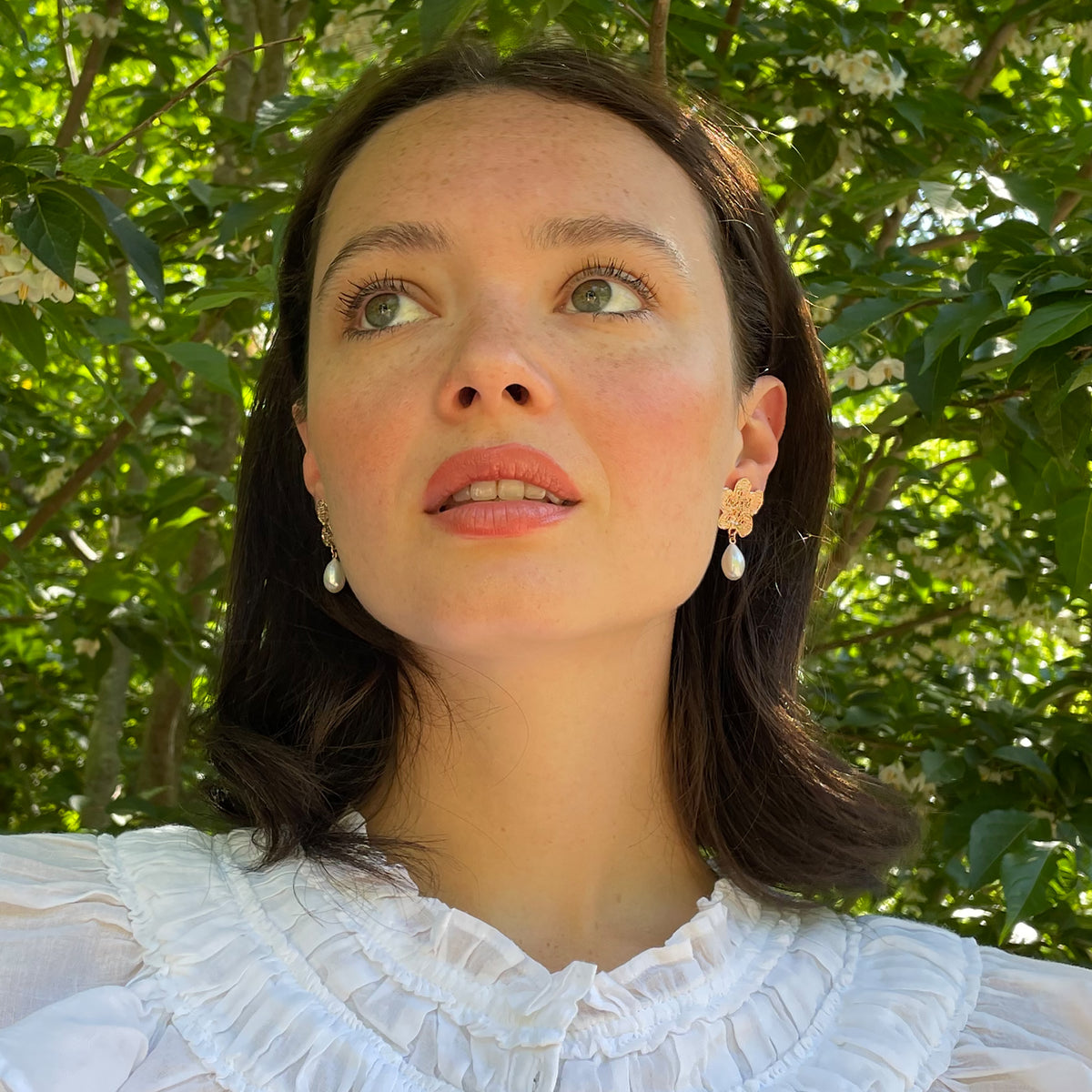 Model wearing pearl earrings with lace flowers in rose gold.