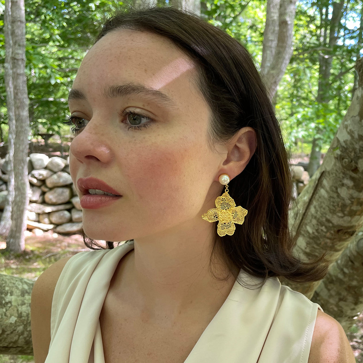 Dangle pearl earrings with large lace flower in 24k gold on a model.