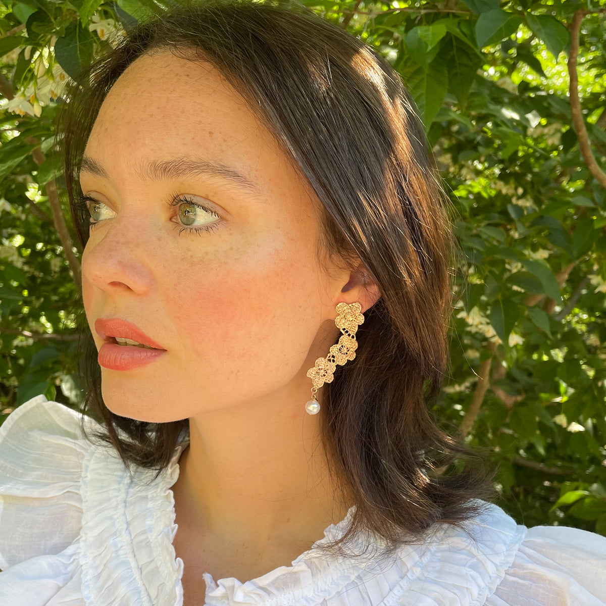 Model showing pearl earrings with lace flower garland dipped in rose gold.
