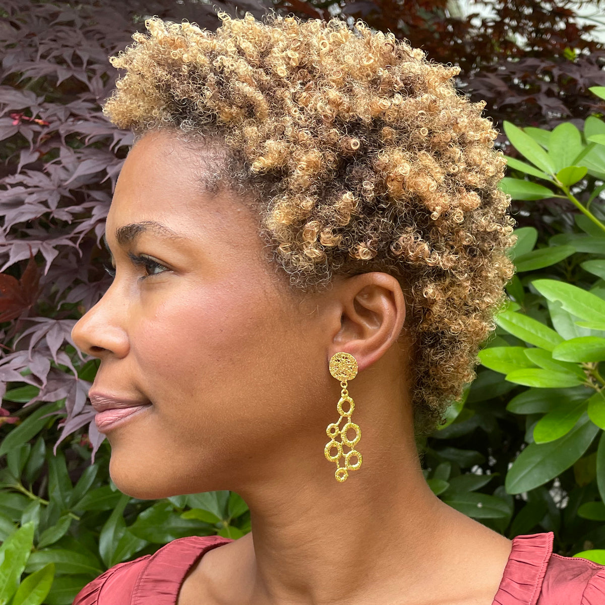 Dana circular lace dangle earrings in 24k gold on a model.