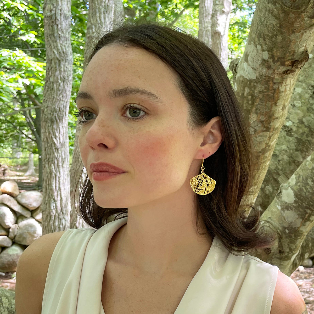 Fan shaped lace earrings in 24k gold on model.