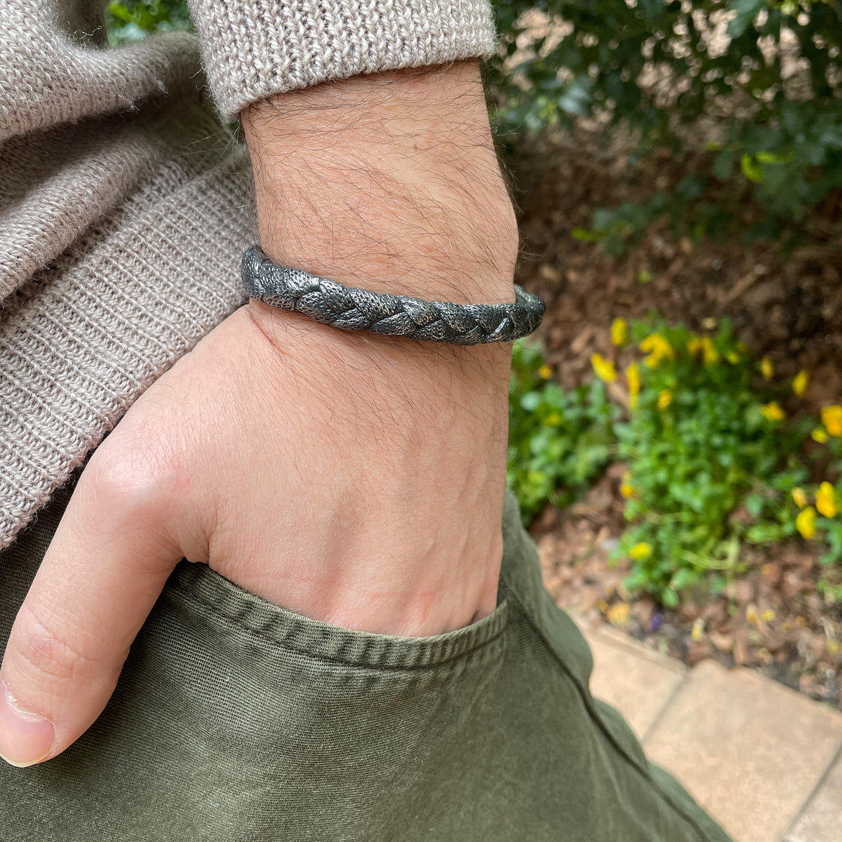 Braided open men&#39;s bangle bracelet in dark oxidized sterling silver on model.