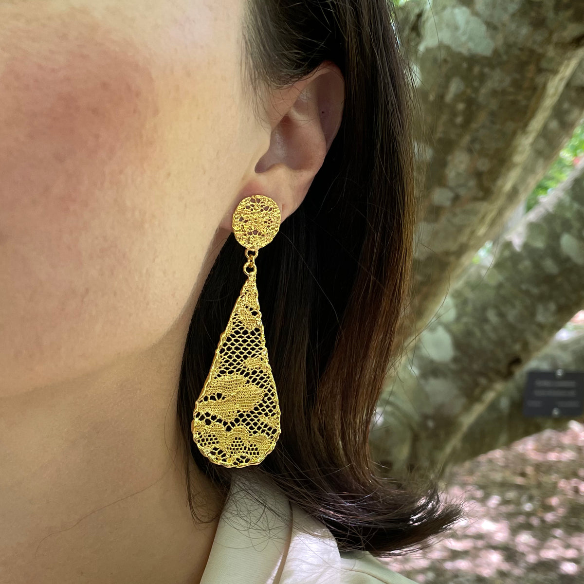 Teardrop lace earrings dipped in 24k gold on model.