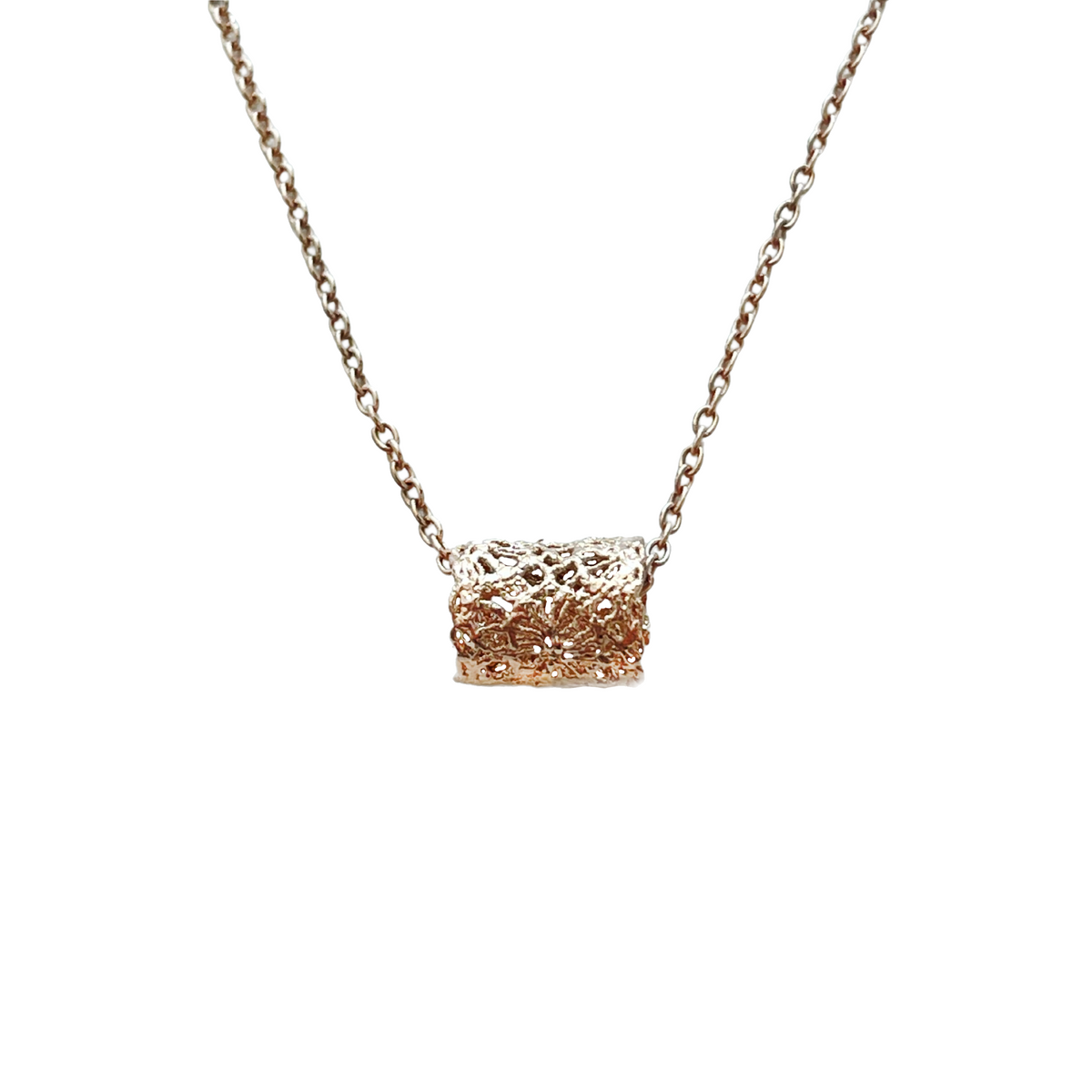 Small lace charm necklace with lace cylinder in rose gold.