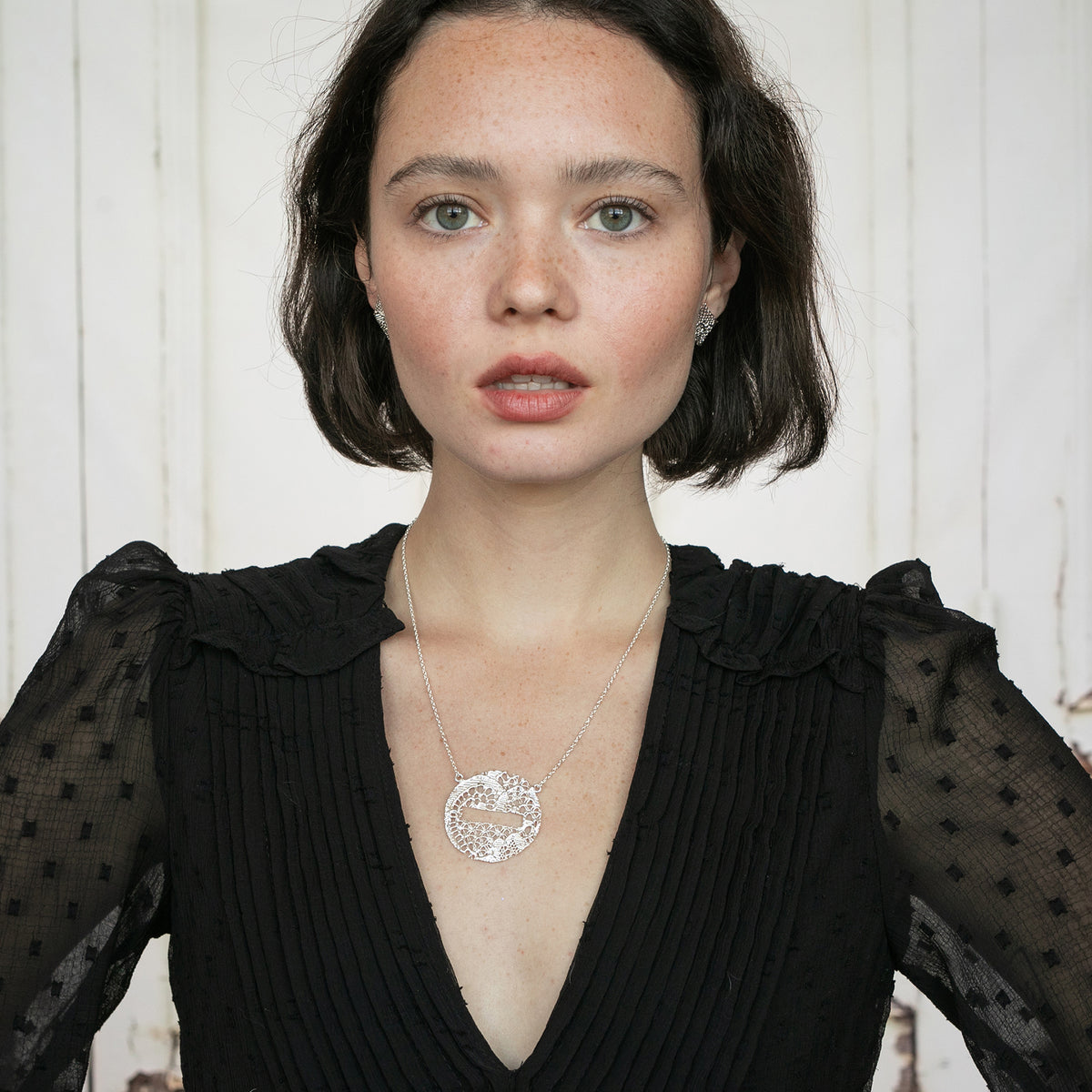Model showing Intricate lace necklace in the shape of a DO NOT ENTER traffic sign in sterling silver.