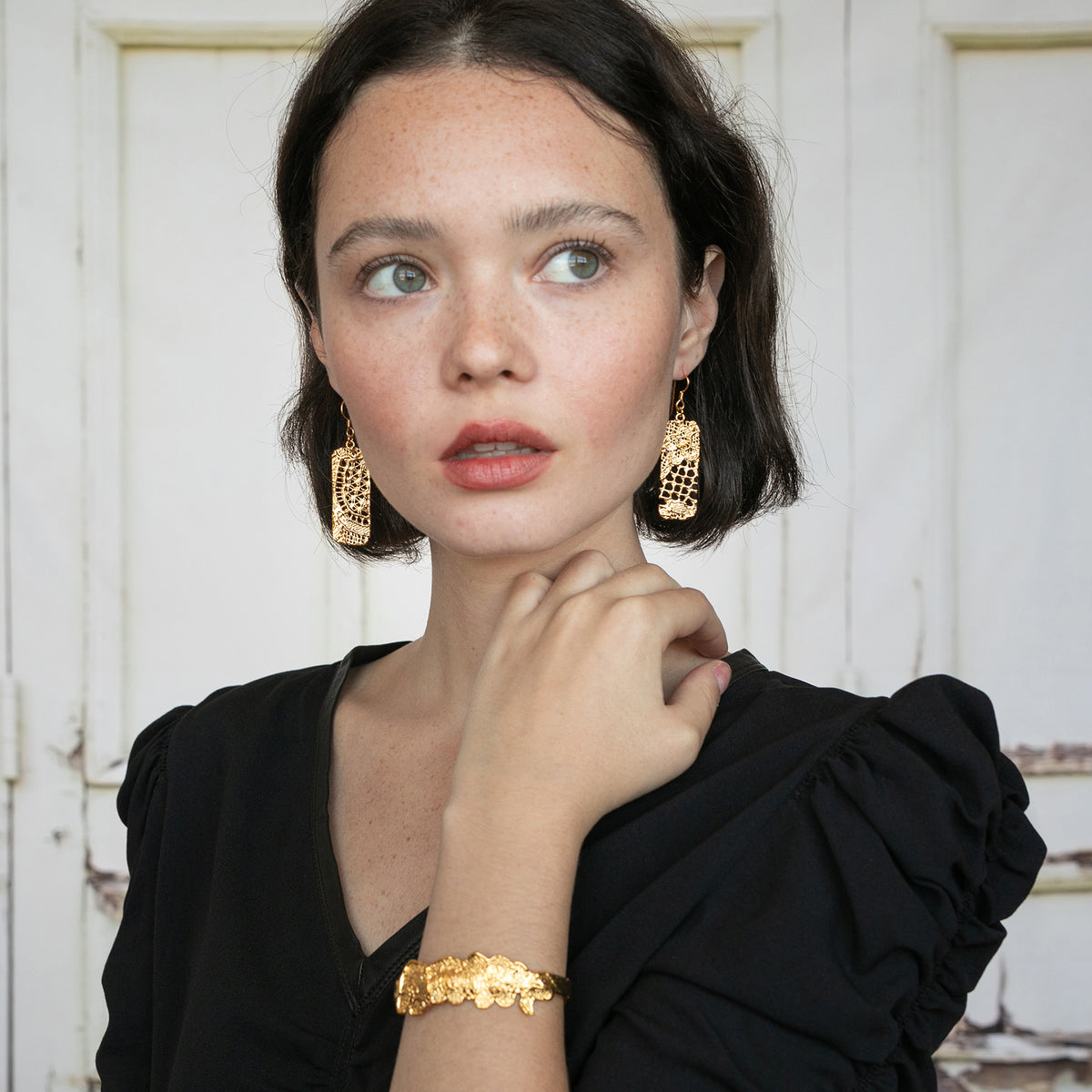 Brilliant Rectangular 24k gold Lace Earrings with French hooks worn by a model.
