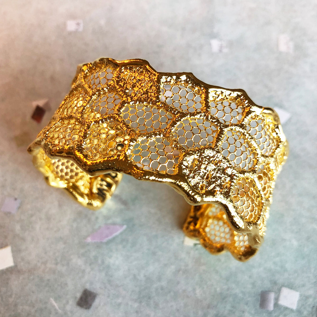Top view of cuff bracelet made from a honeycomb lace dipped in 24k gold.