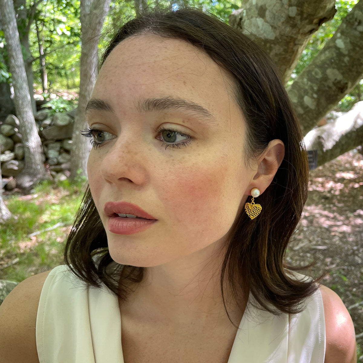 Model wearing pearl earrings with 24k gold lace heart.