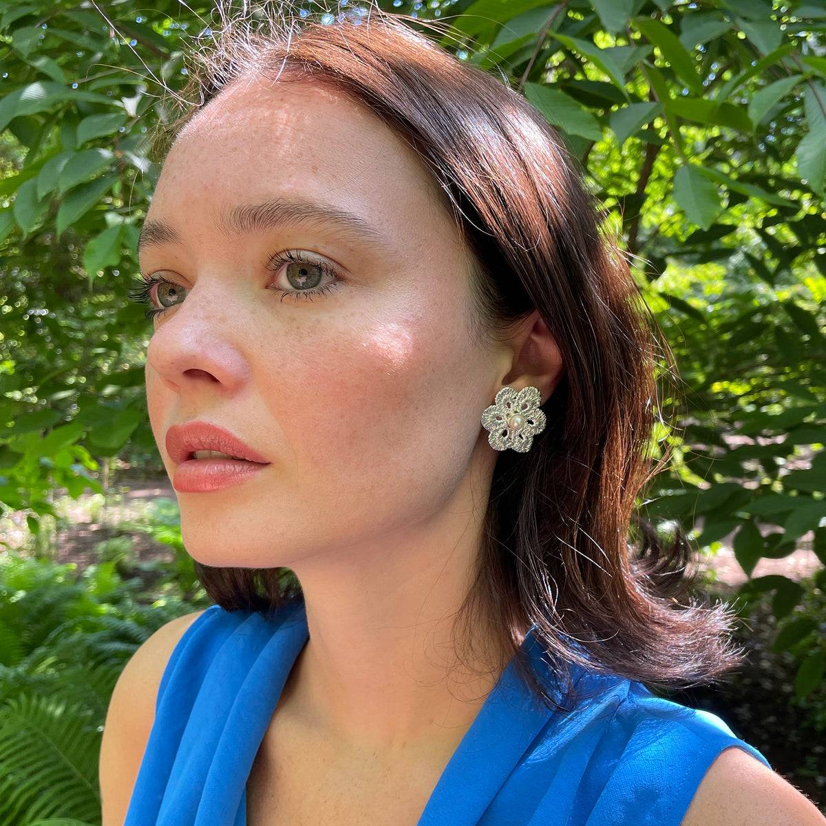Pearl stud earrings with lace flower in sterling silver on model.