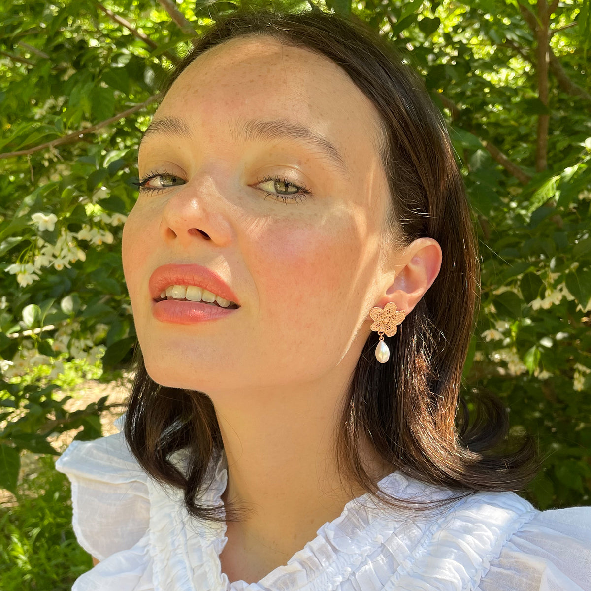 Model wearing pearl earrings with lace flowers in rose gold.