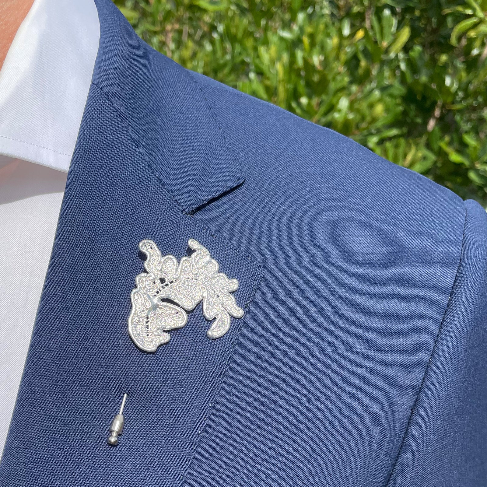 Lapel pin in the shape of a lace feather dipped in sterling silver.