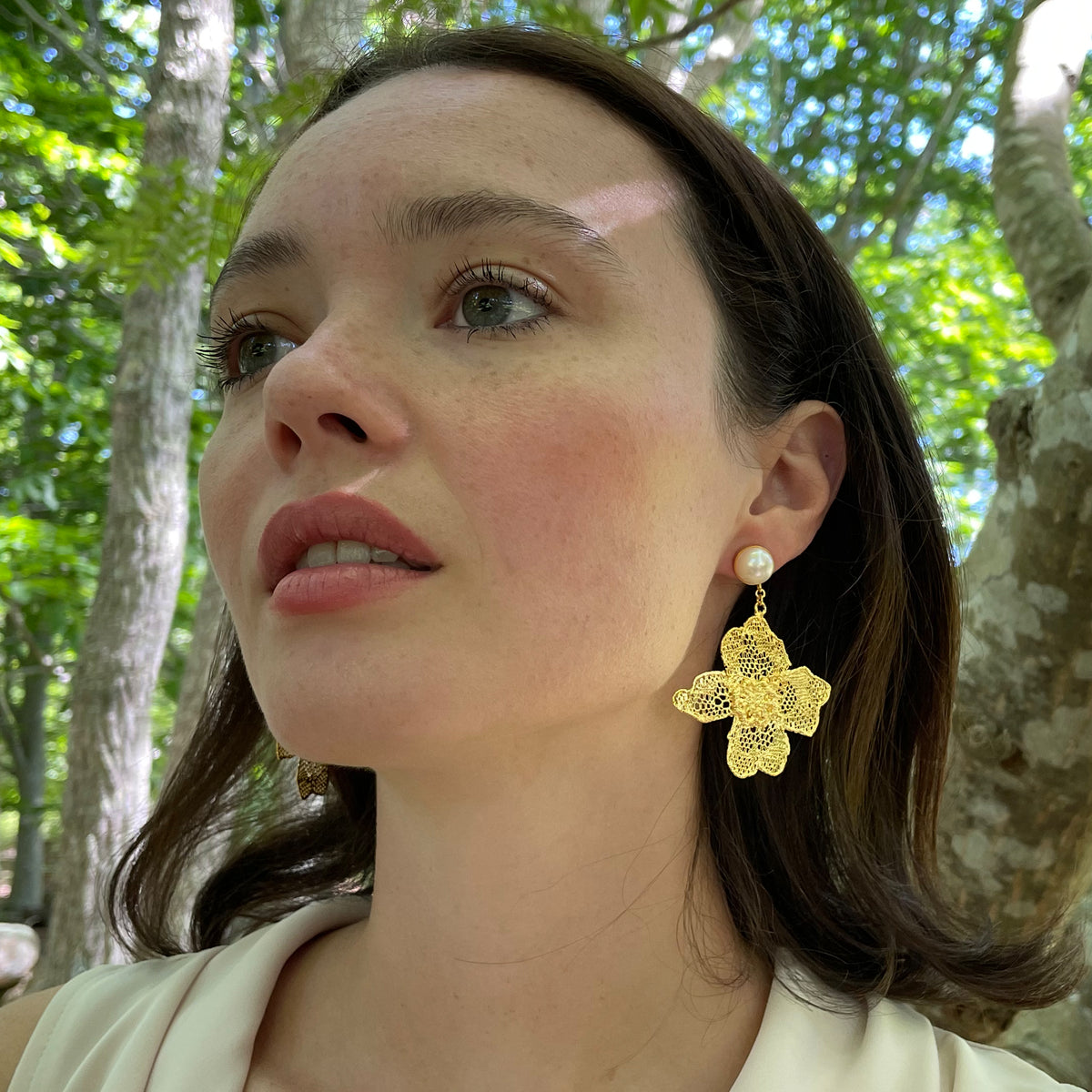 Dangle pearl earrings with large lace flower in 24k gold on a model.